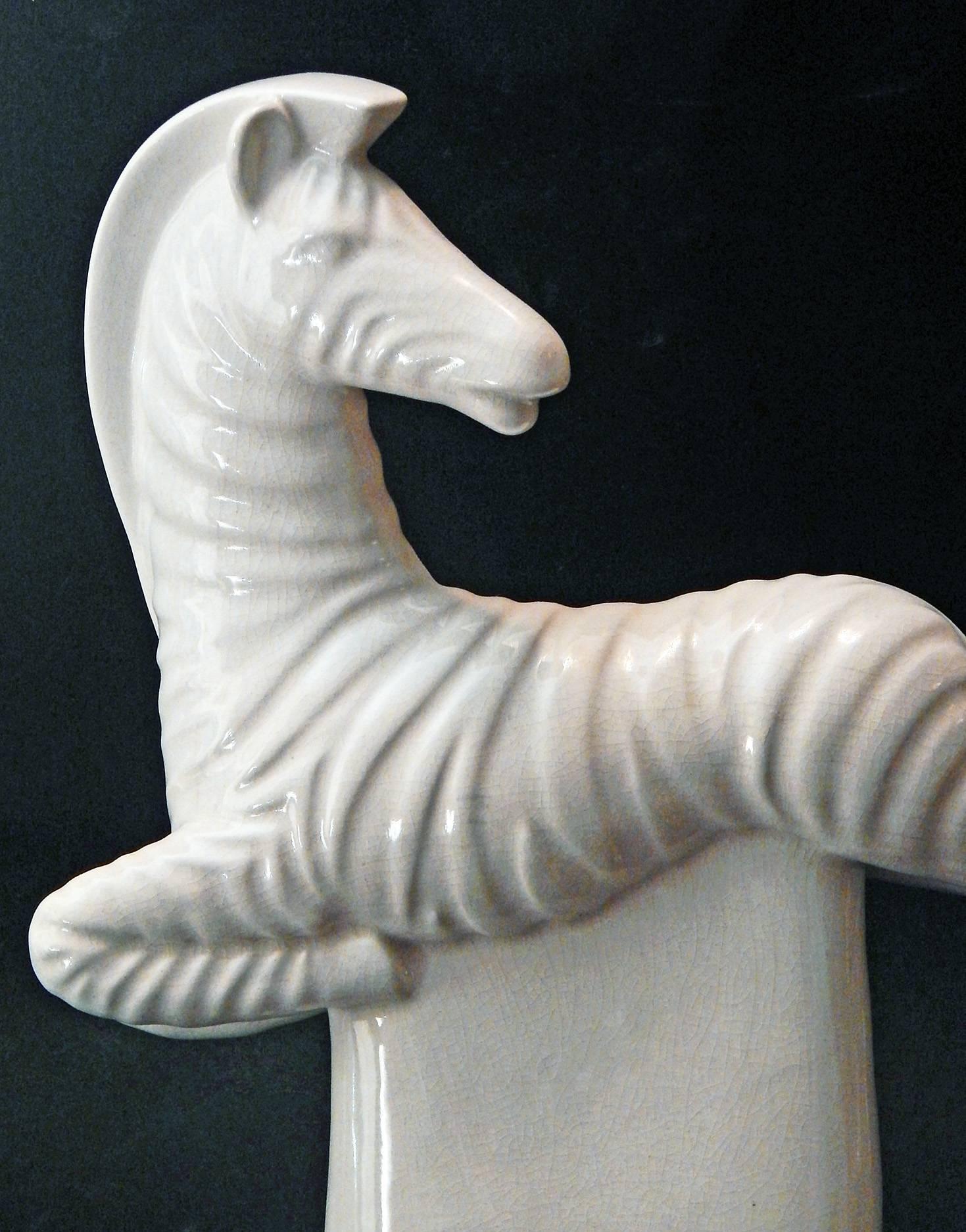 Full of energy and élan, this rare sculpture by Waylande Gregory, dating from the 1940s, depicts a zebra in mid-air, looking behind with elegant unconcern. The ceramic form is glazed in a lovely off-white glaze, and is mounted on a dark-stained
