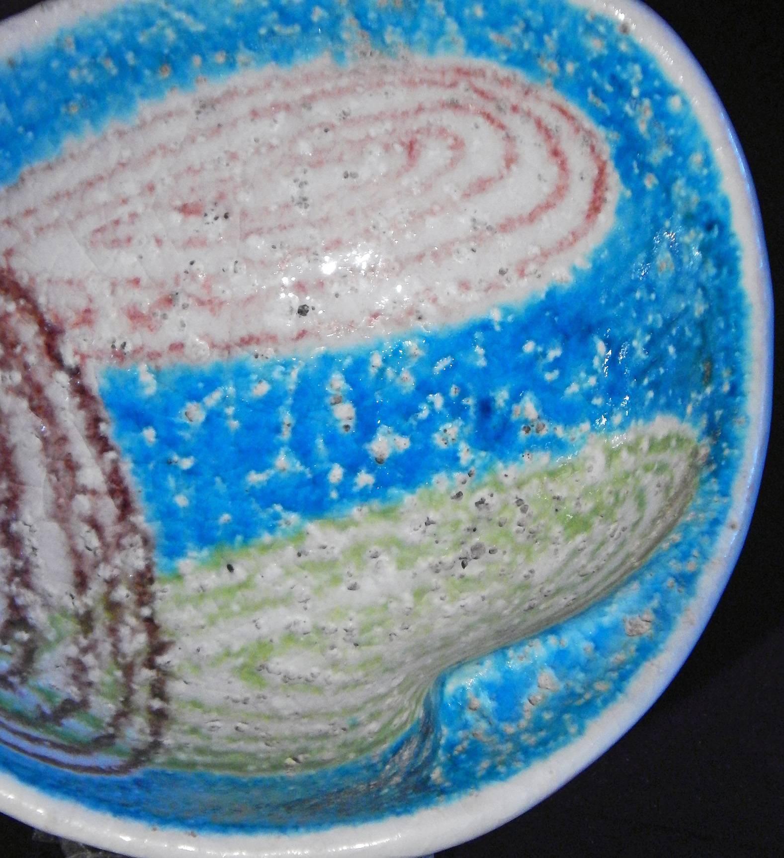 Brilliantly glazed in tones of turquoise, cerulean, oxblood and lime, this small and unique dish was commissioned and sold by Raymor, a New York-based company that commissioned pieces from around the world. This piece was made in Italy, possibly at