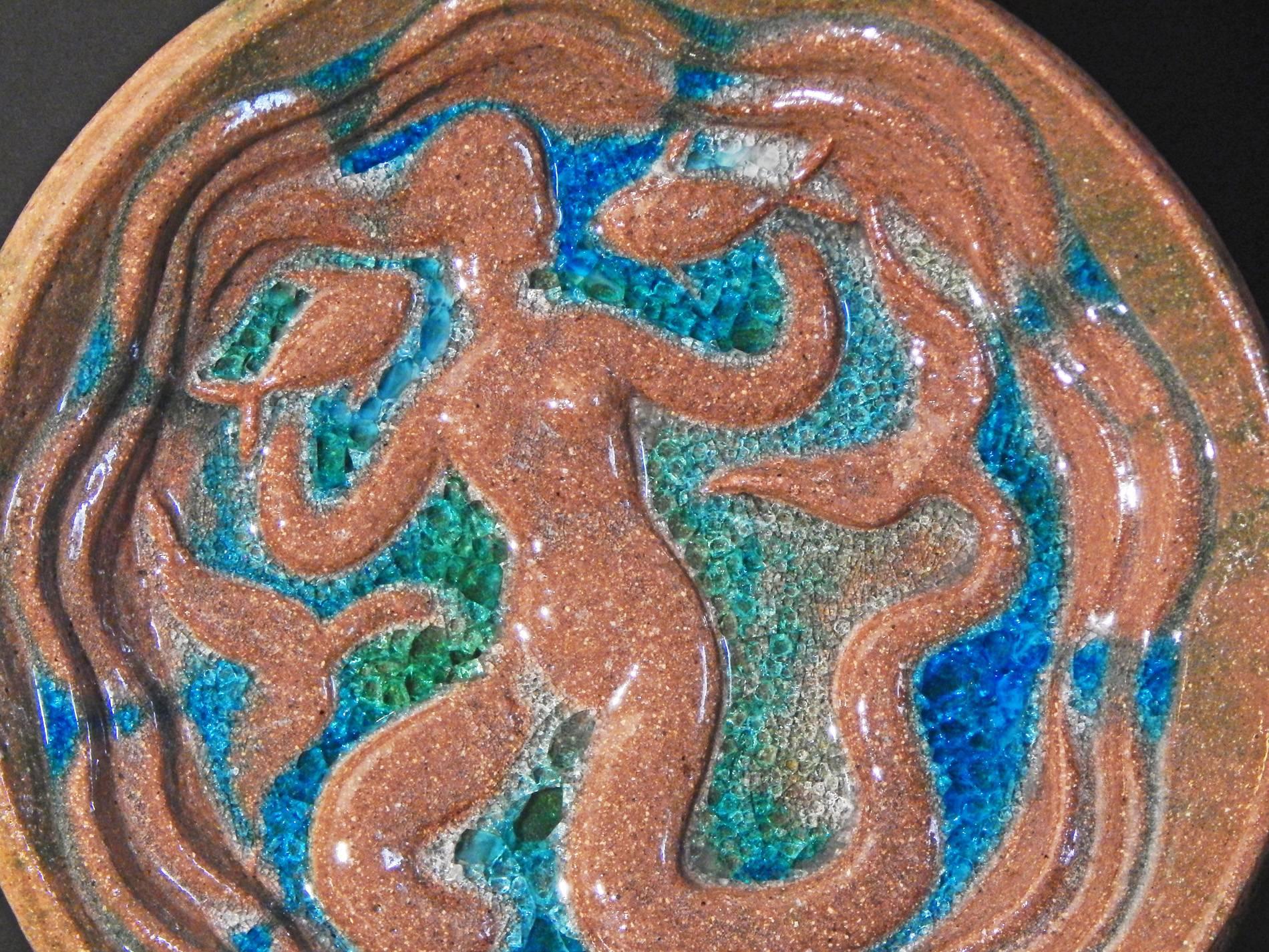 Créé par l'un des plus importants sculpteurs américains de la période Art déco, ce grand et lourd bol sculptural de Waylande Gregory représente une sirène tenant un poisson dans chaque main, entourée des bleus et verts brillants de la mer. Gregory