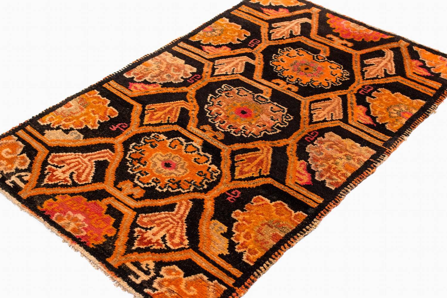 Deco-esque floral designs and grid-work cover the field of rich espresso brown in this 1930s carpet. Intricate designs are woven in rich orange, cinnamon brown and coral red, with touches of navy and slate blue. The carpet's border features unique