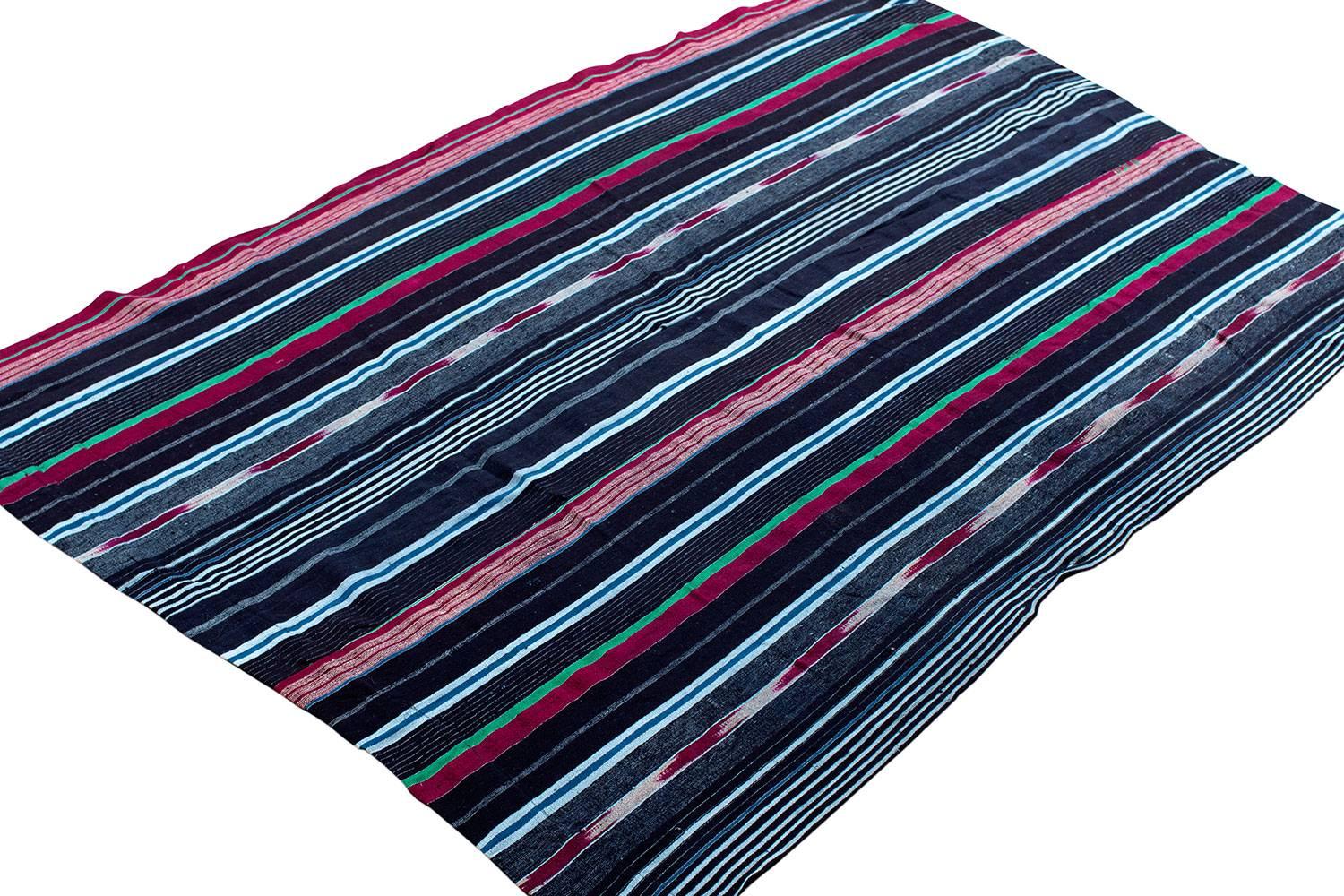 This textile is a superb Yoruba men's wrap cloth. The fine ikat pattern is rare for aso oke textiles from the Yoruba people from around mid-20th century. This textile is woven with lush magenta, green, and indigo colors. This textile was woven by