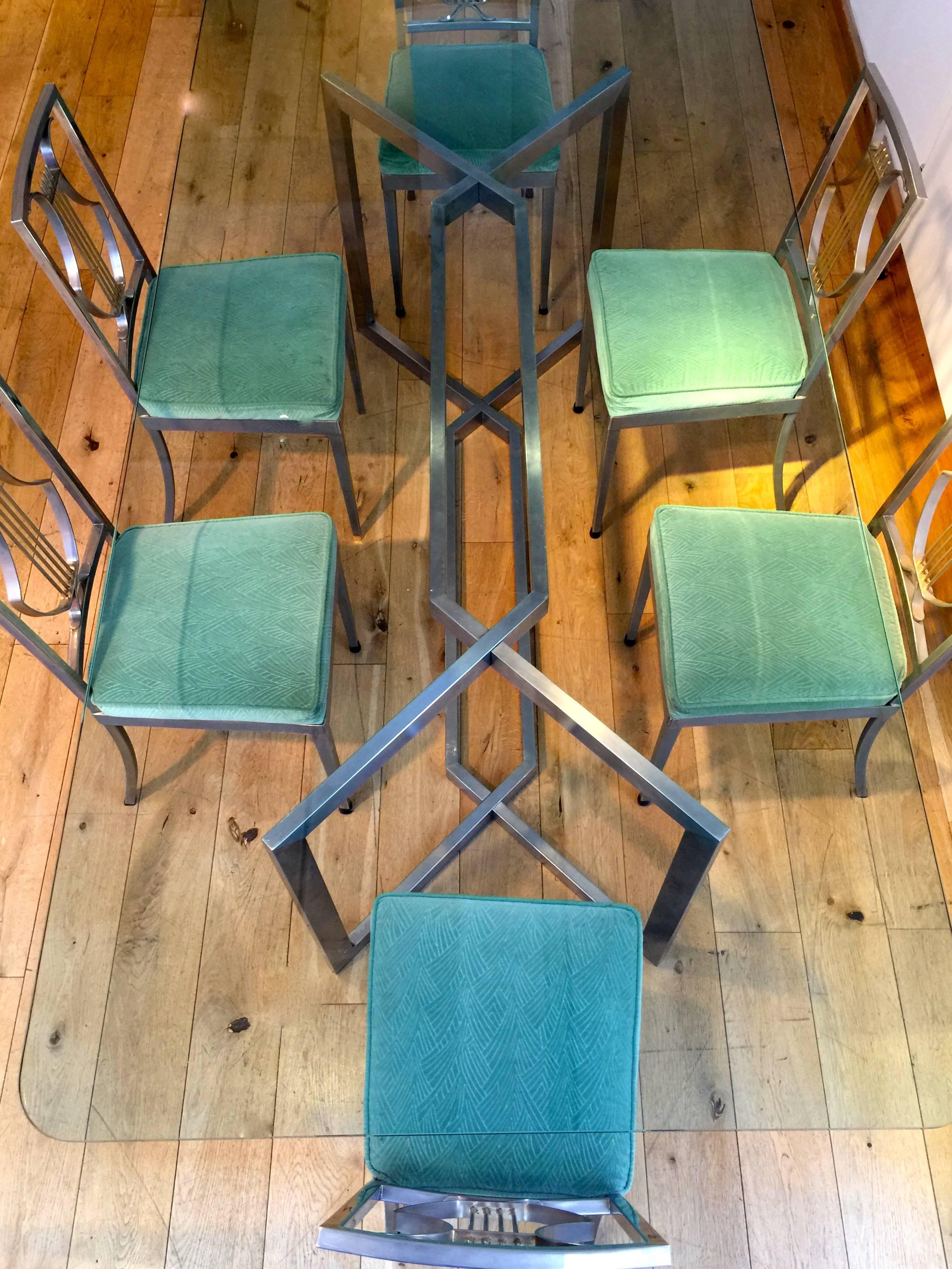 Brushed stainless steel dining table by Paul Legeard, for Dom, 1970s 
Set of six steel dining chairs, attributed to Maison Jansen, 1970s, with lyre back splats and seats covered in eau-de-nil fabric with stylised leaf frond design
NB The glass