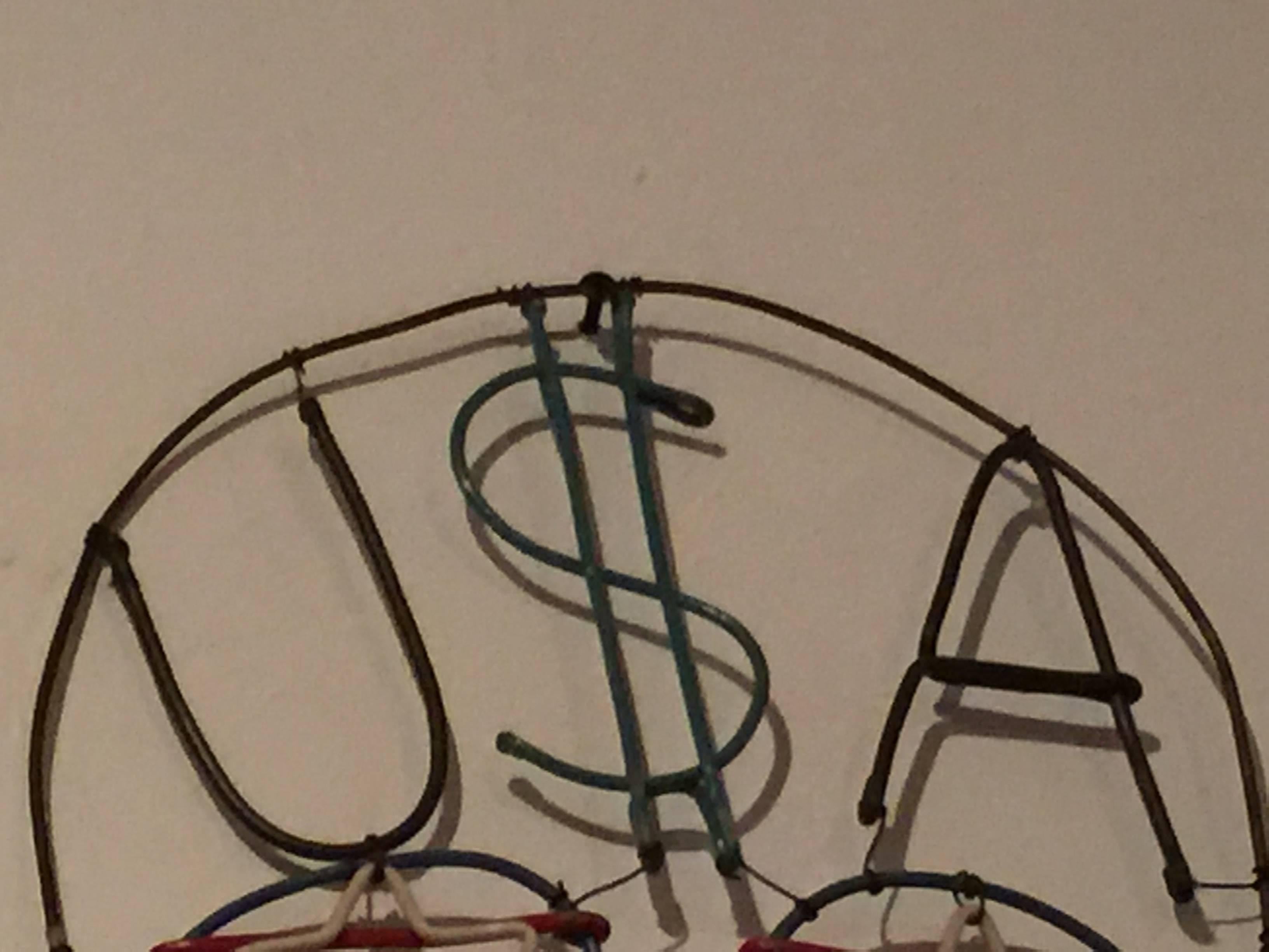 Handmade wire and wood skull. The S in USA has been augmented into an dollar sign.