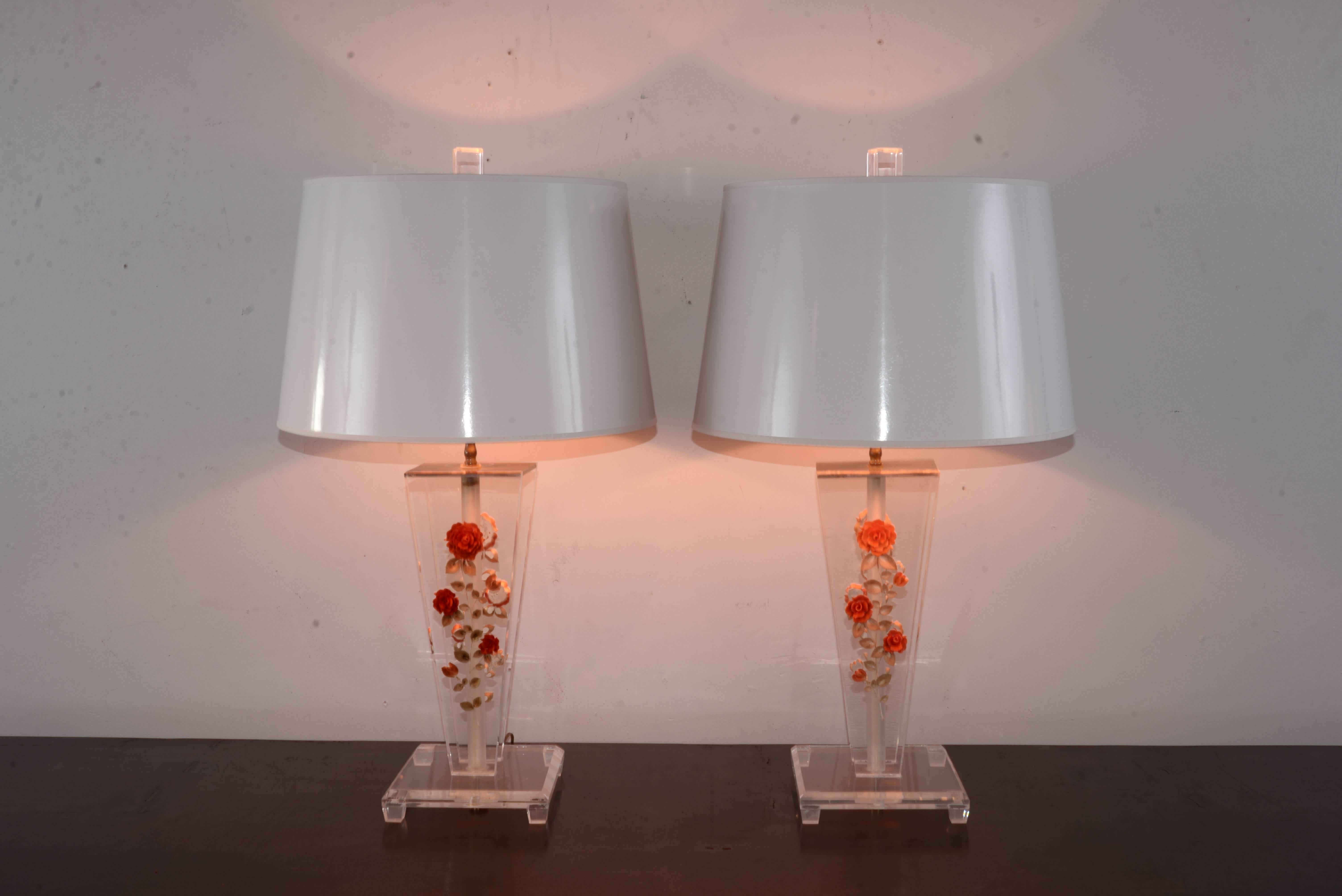 Pair of Lucite table lamps with unique three dimensional flowers embedded in the Lucite. New custom-made white gold lined shades have been added.