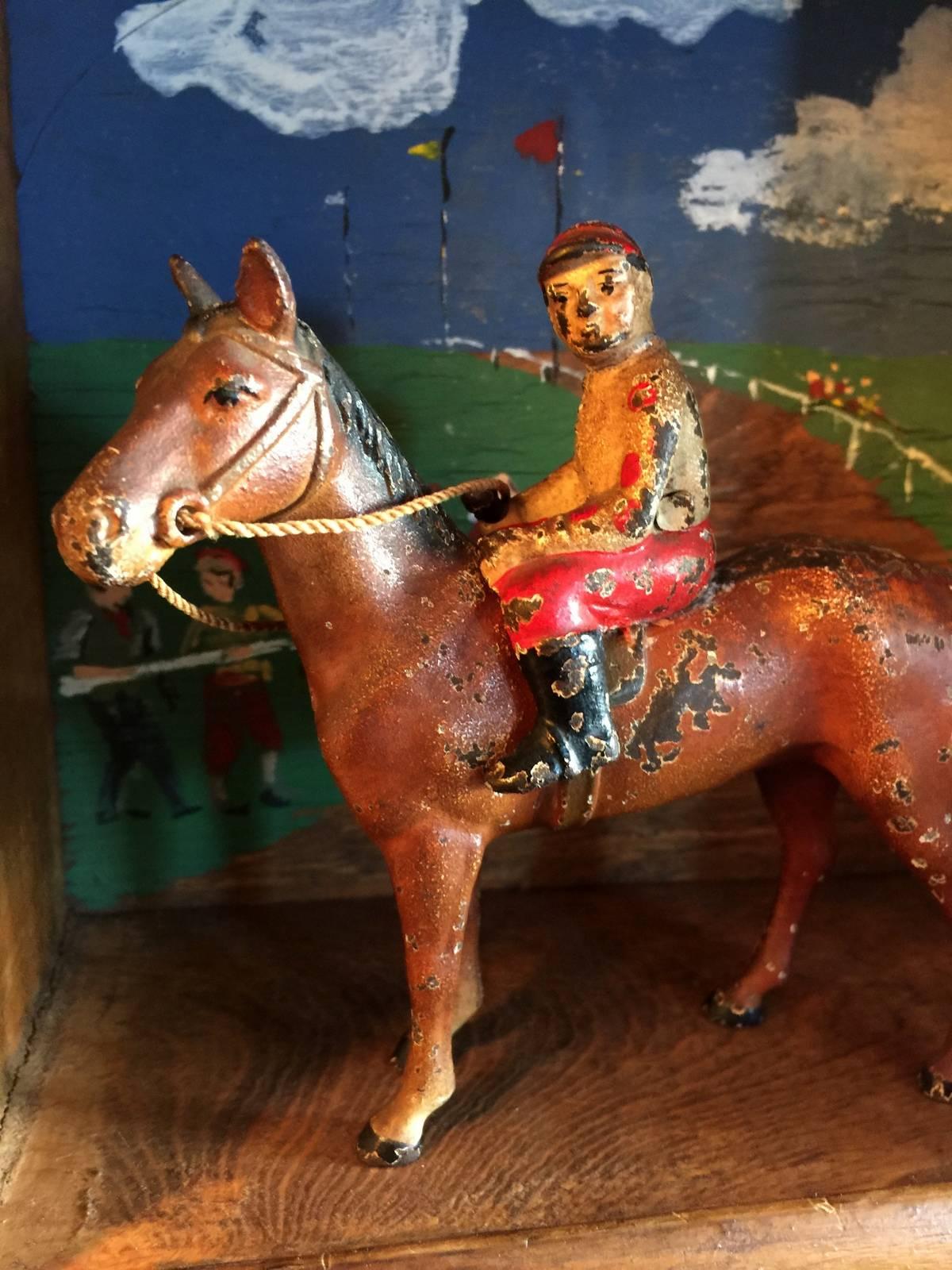 Wall-mounted wooden framed shadowbox horse track with scenic background adorned with a cast aluminum horse and rider.