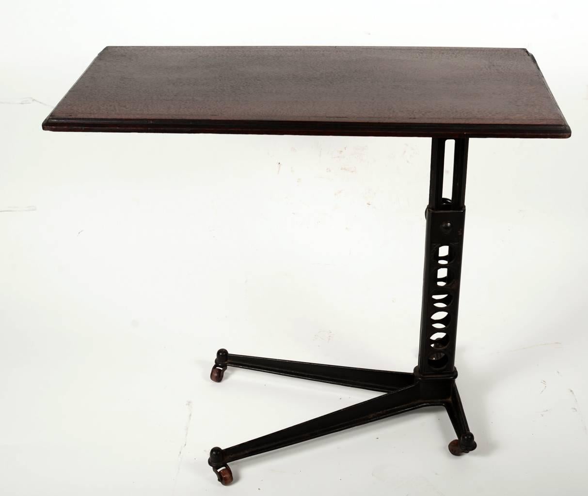 Early century adjustable height workstation with wood top and wood casters. The wood top of this piece rotates 90 degrees and the height of this table adjusts from 24"-34".