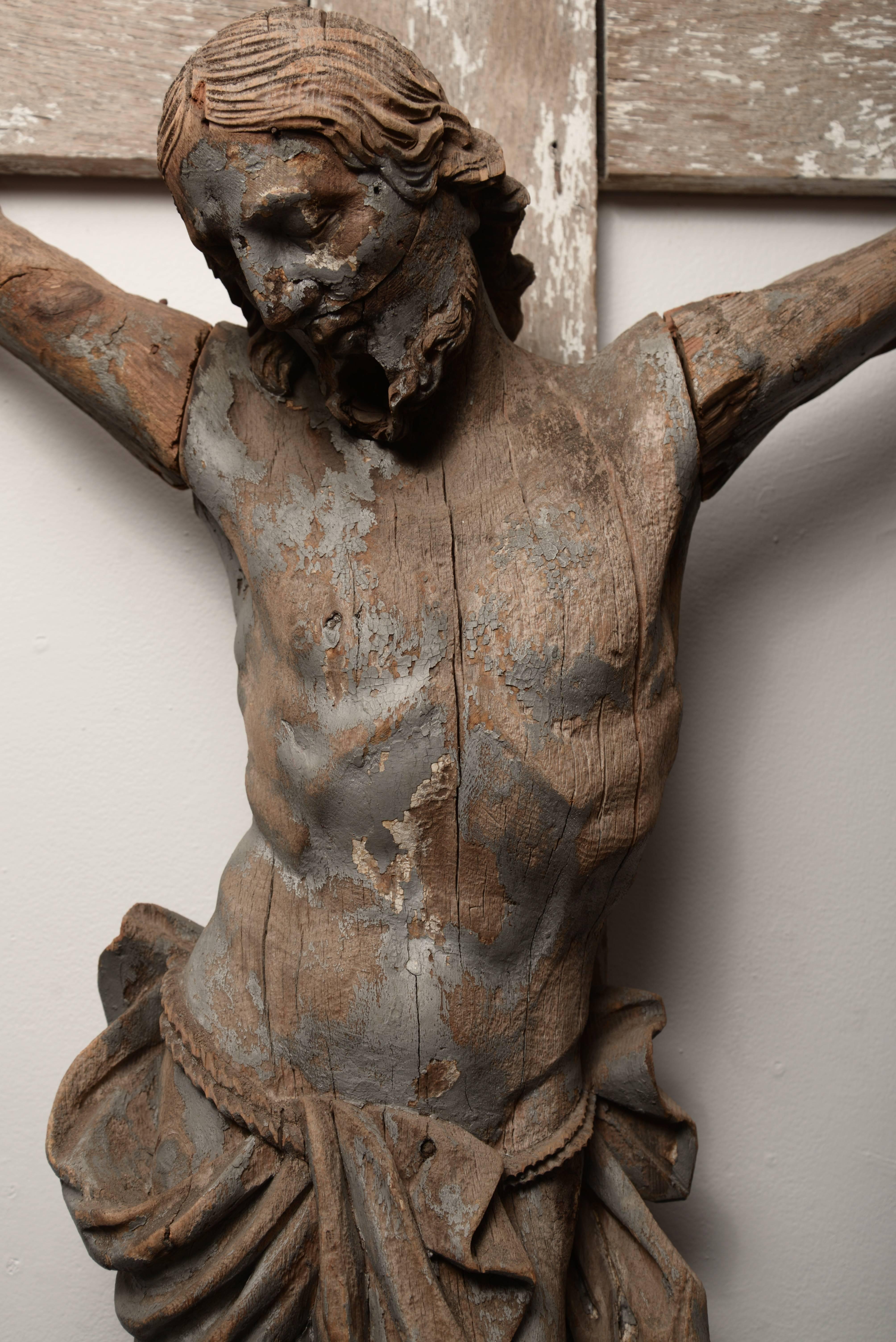 Wooden hand-carved crucifix with remnants of silver paint and white paint.
