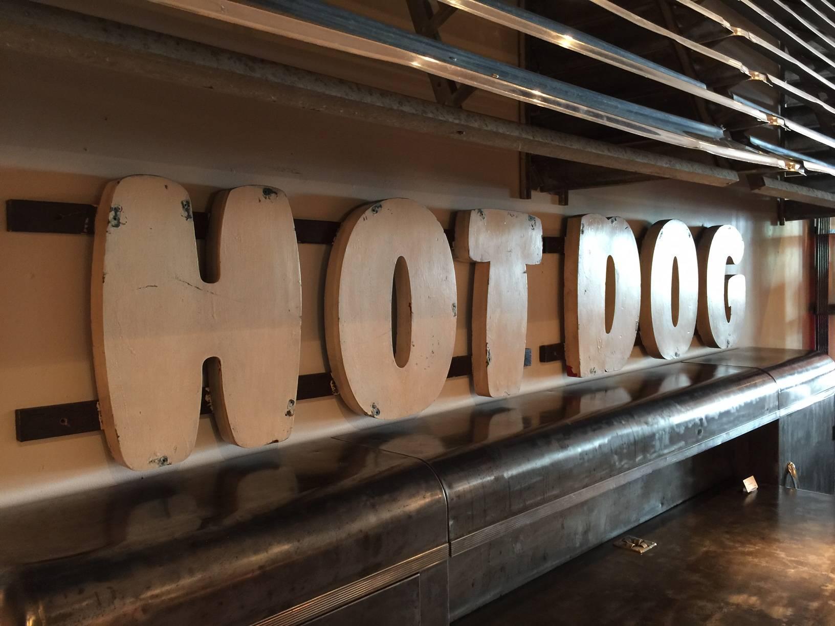 Off-white wooden hot dog sign from 1970s San Francisco restaurant.