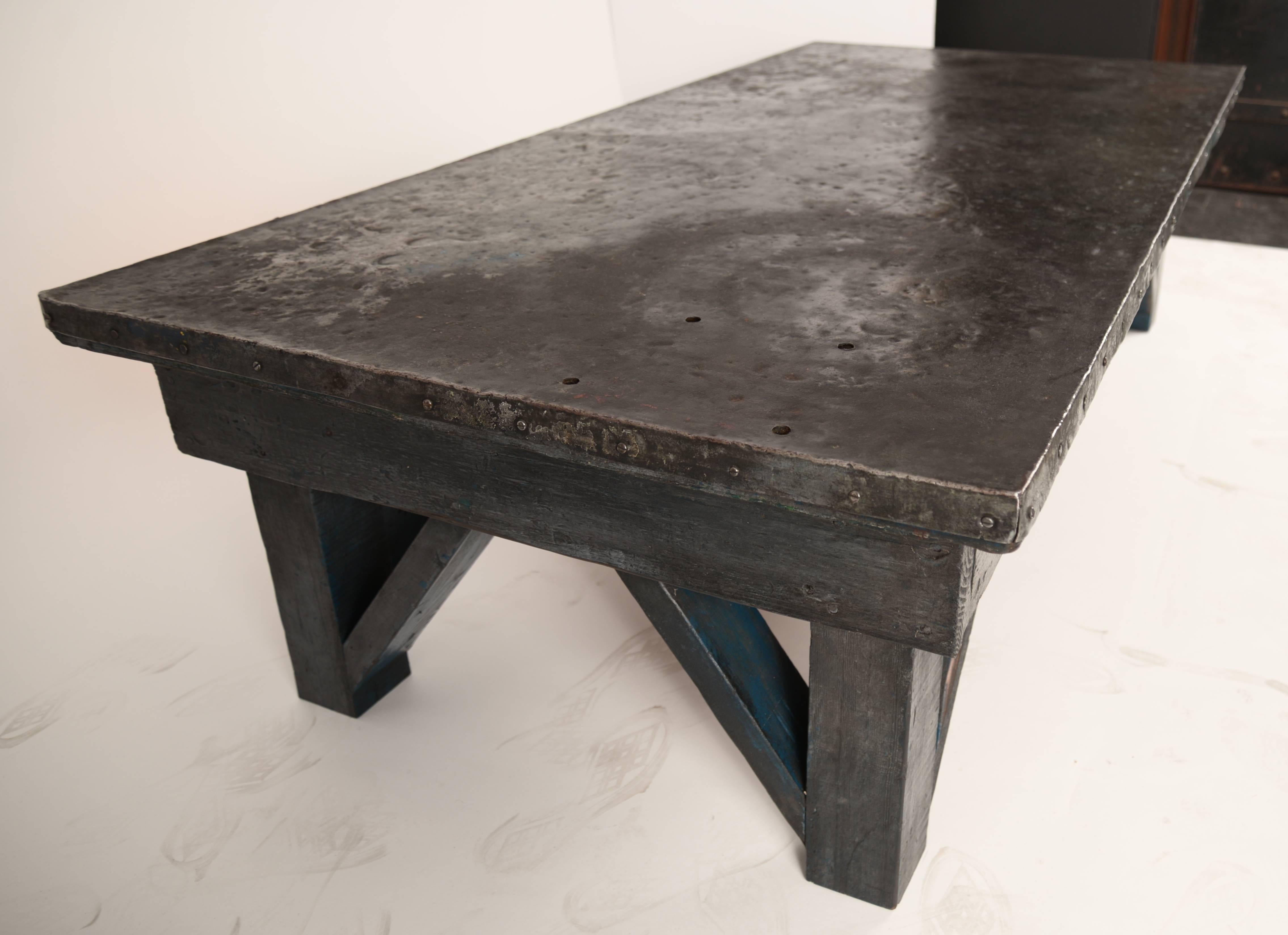 Steel capped wooden low work table. The patina is perfection without any sharp edges or breaks. The gray painted base and the top have been thoroughly cleaned and waxed. This would be equally at home as a coffee table or a bench.