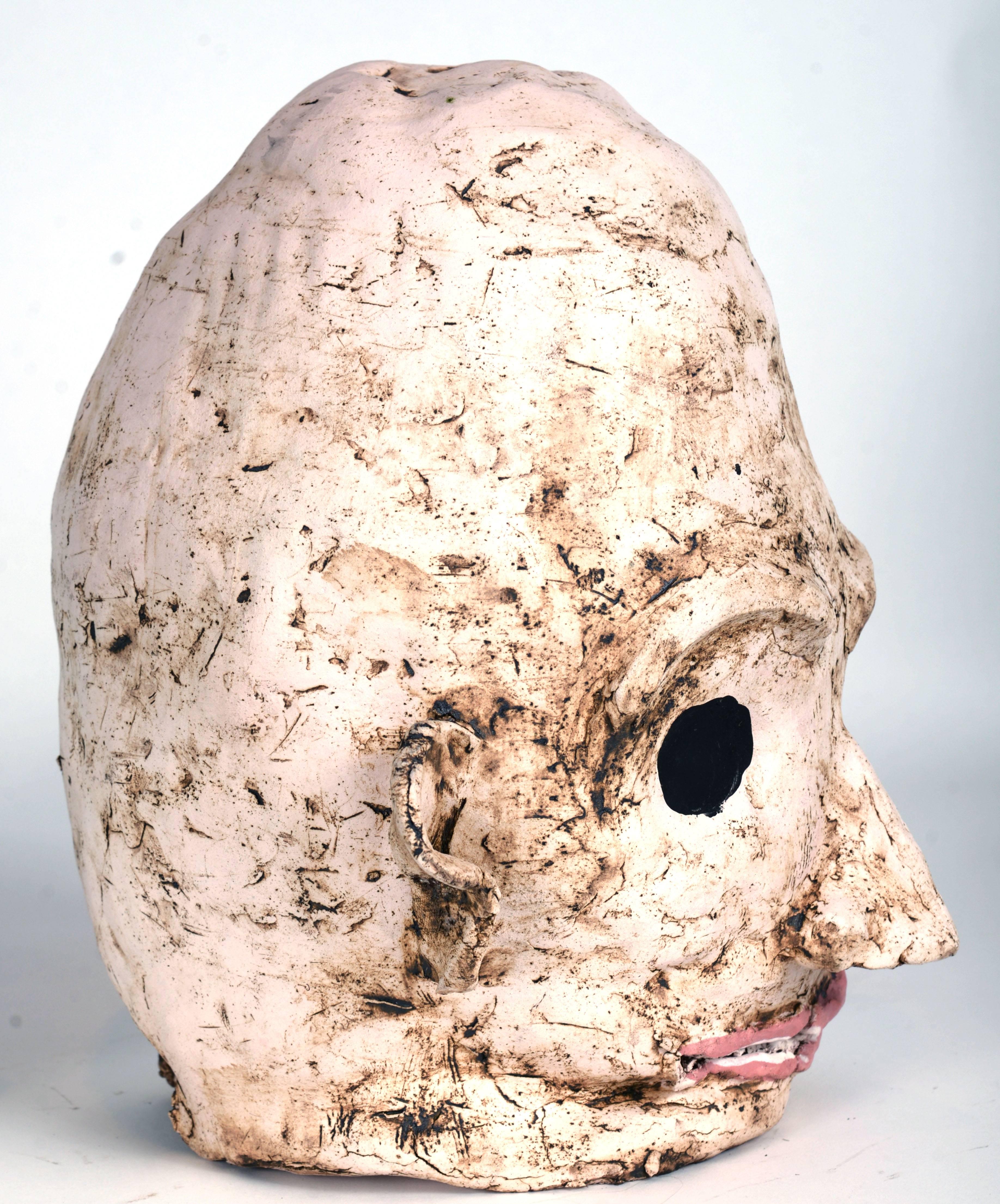 Large-scale ceramic alien head with an exaggerated dome shaped head, black eyes and pink lips. There's a small break in at the base of the back of the head which appears to have happened during firing.