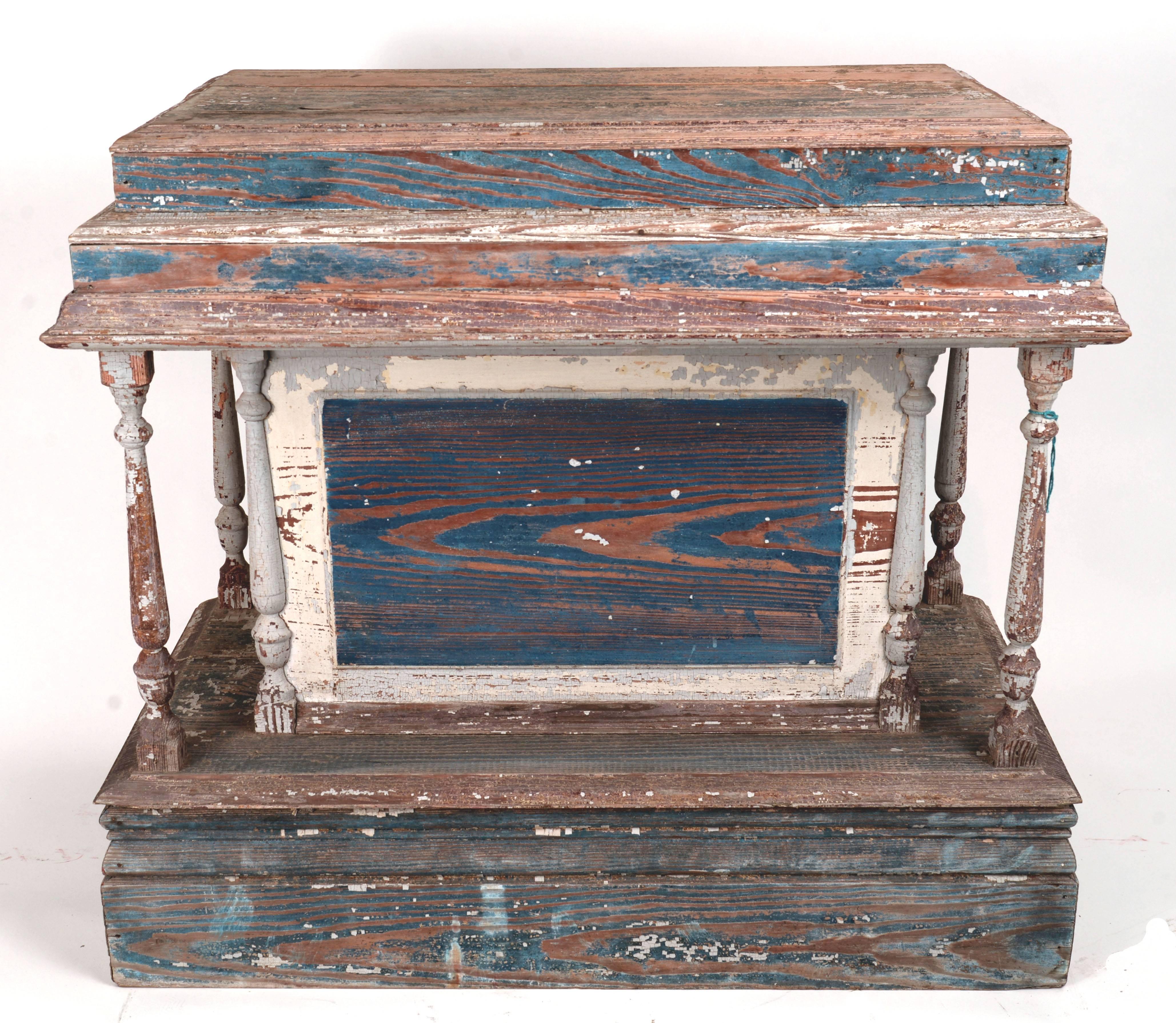 Ornate four spindle two-tier wooden station with blue and white over-paint. The back of this piece is open with two wooden shelves.