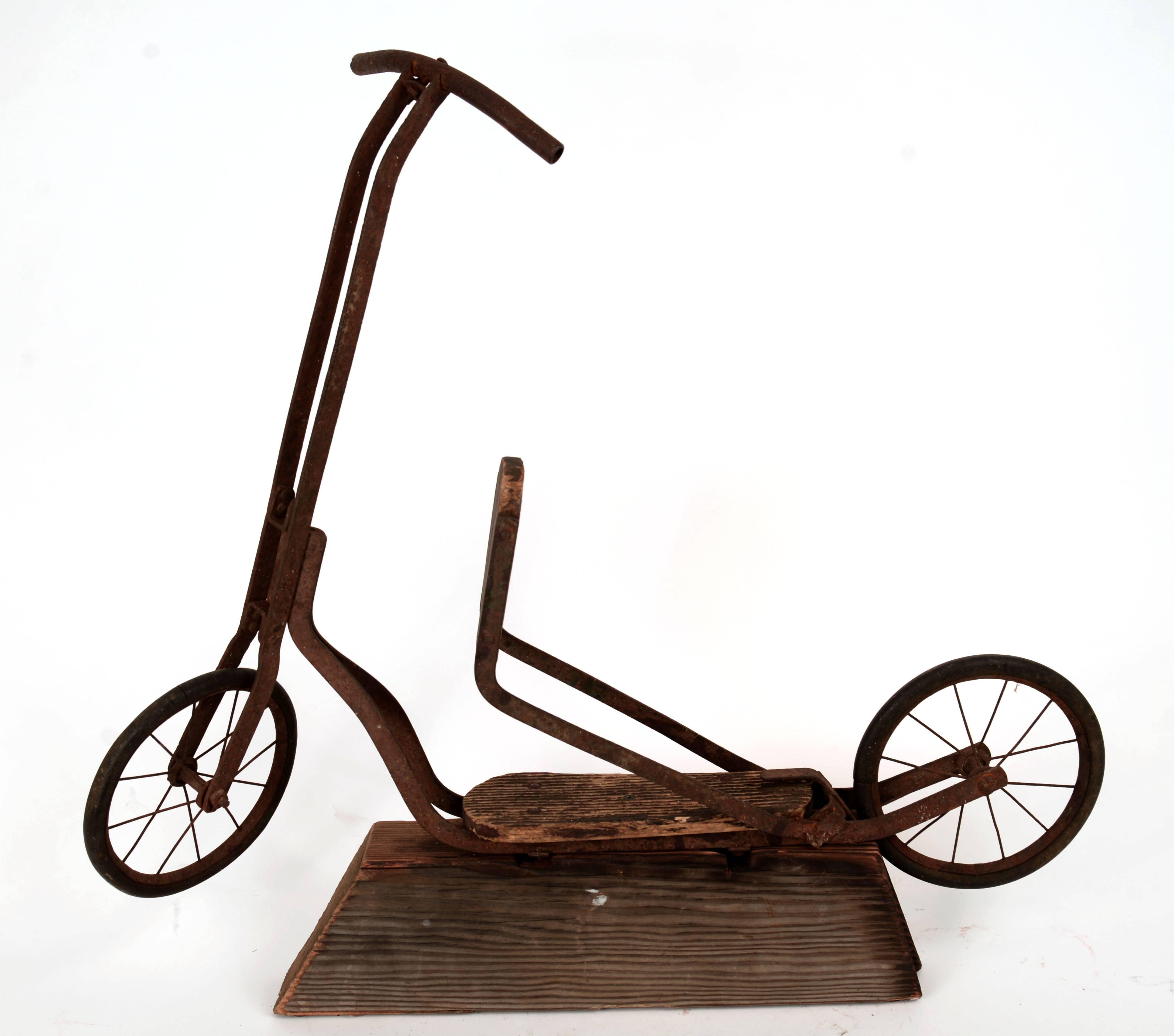 Unique flip seat turn-of-the-century scooter on a wooden stand. There is a great deal of decay and surface rust to this decorative object but it is still fully intact and super cool.
