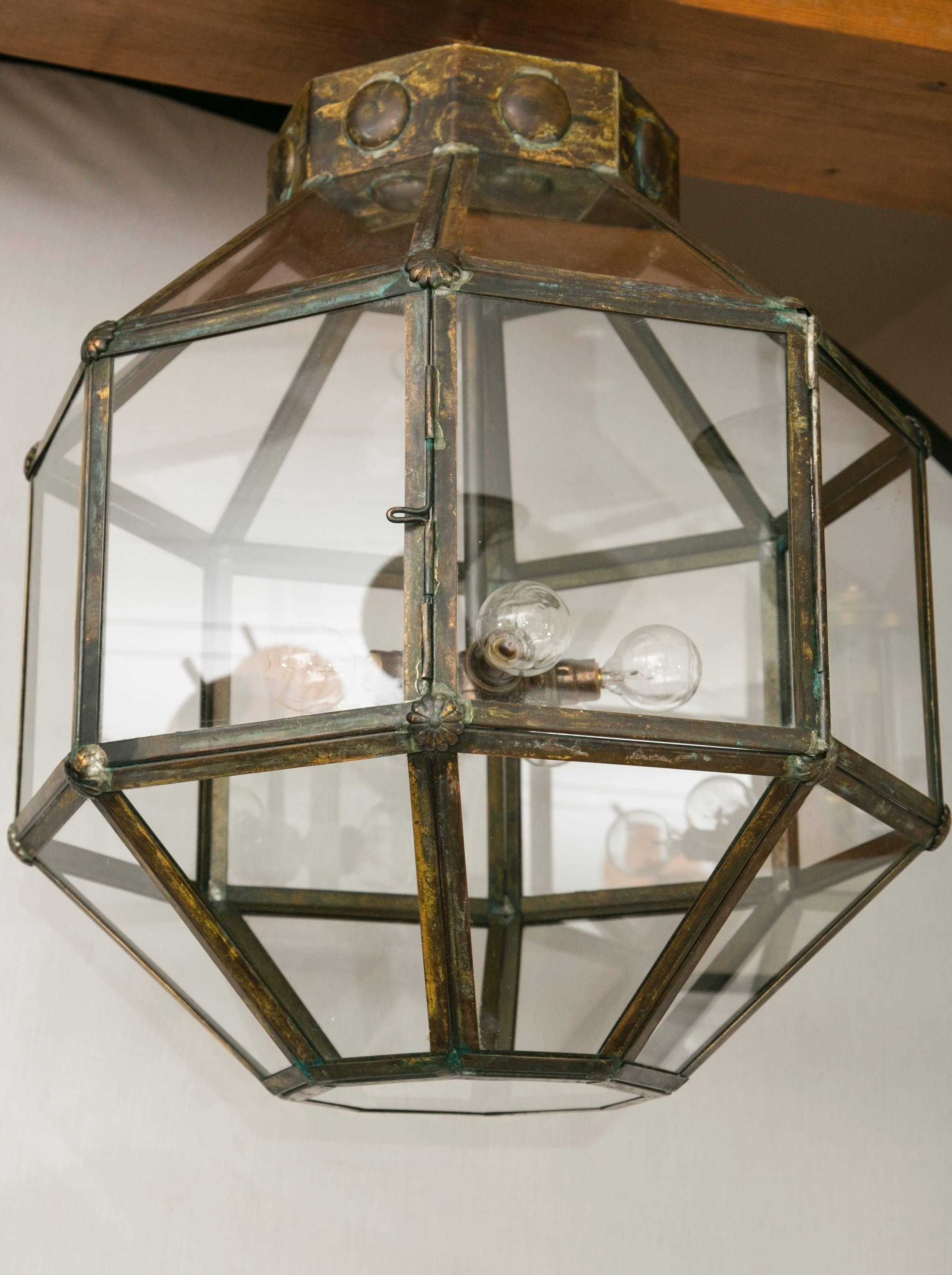 Minimalistic pair of antiqued brass octagonal lanterns recently illuminated with five light interior chandelier
can be installed with three smaller chains or a larger single chain with canopy.