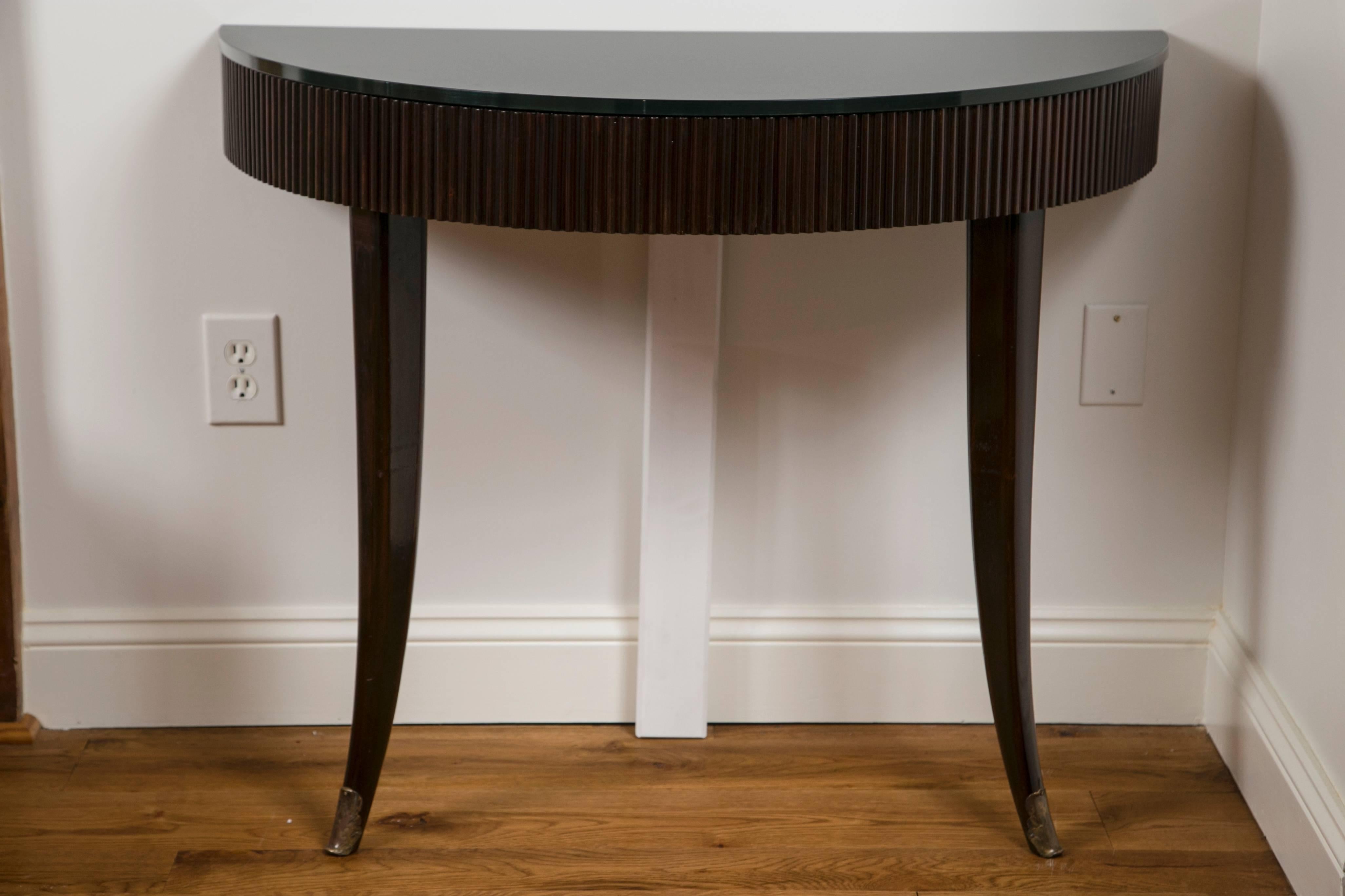 Cool pair of Italian demilune console tables in walnut with ribbed apron and elegant splayed legs finishing with brass sabots, new thick black glass tops, Milan, circa 1940s.
Glass tops new.
(White stand is to be removed as this is to display in