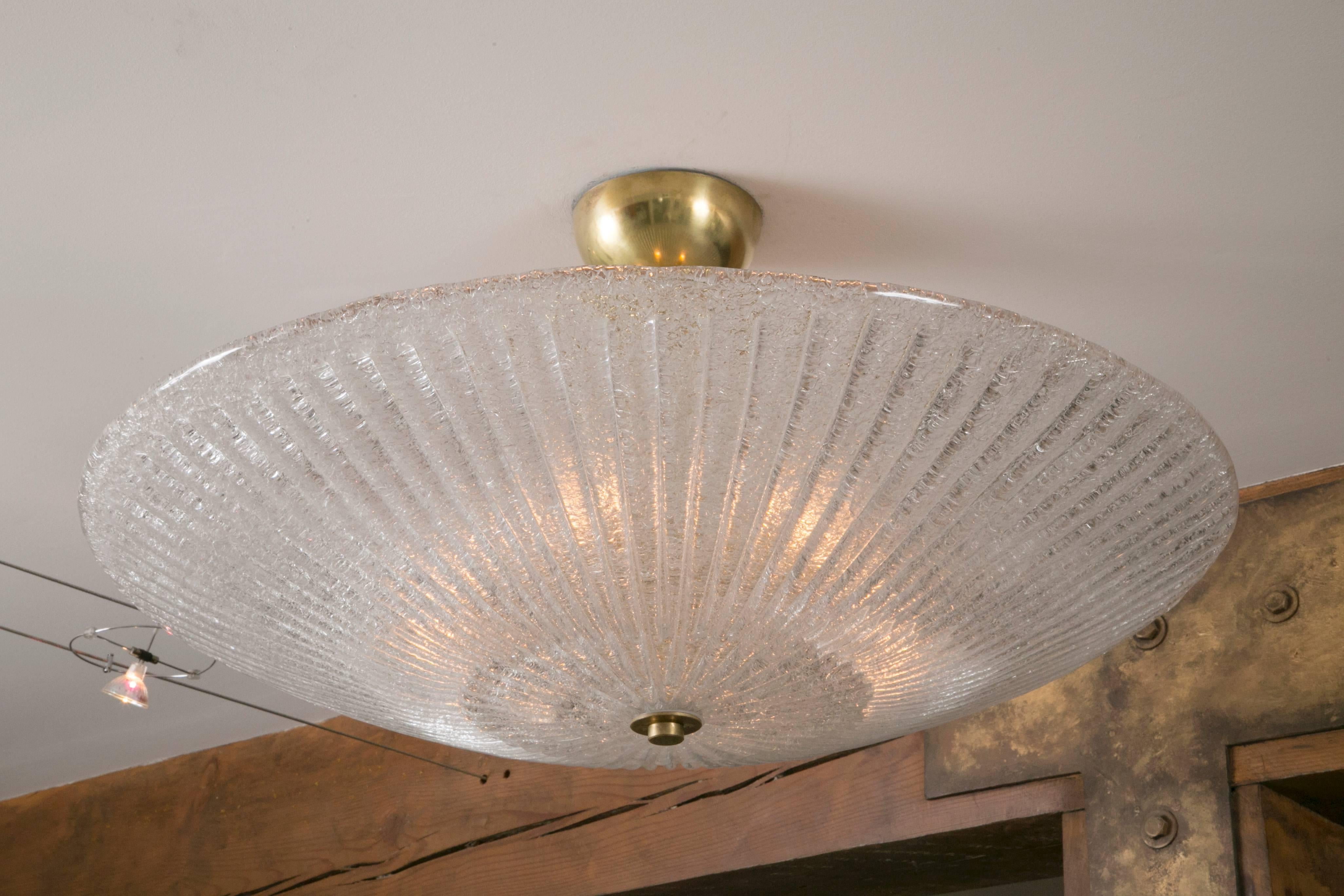 Circular-shaped and reeded Murano blown ceiling fixtures blown in a clear color with unlacquered brass fittings. Note lovely uneven edging and light bulbs spotting is not evident as this is thickly blown and contains a light icy