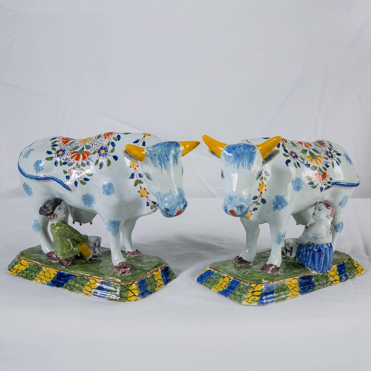 A pair of Dutch Delft cows painted in bright polychrome colors of blue, orange, yellow and green.
This is a wonderful pair of Delft cows each with a seated boy or milkmaid milking.
 The back of each cow is covered with lovely painted flowers. A