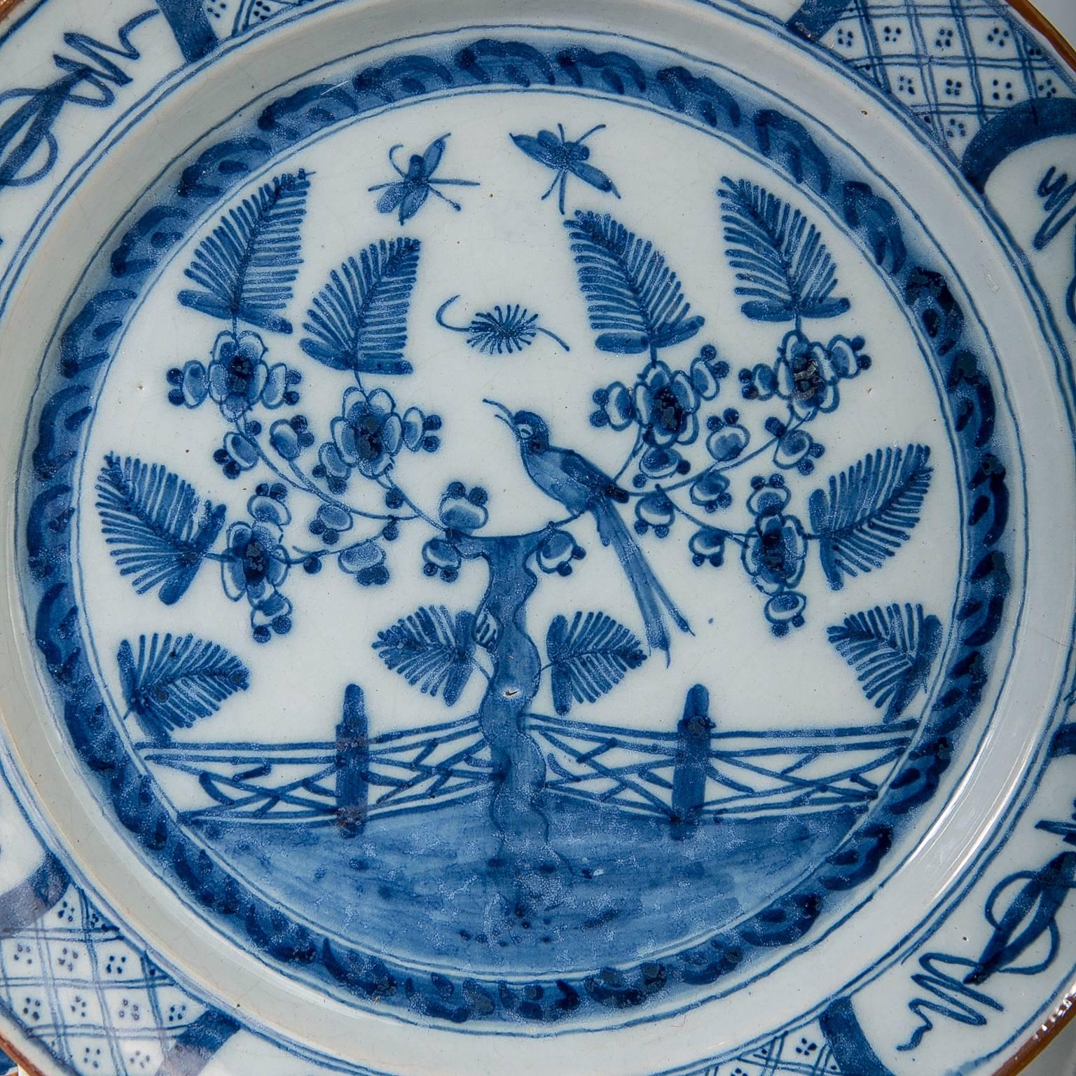 A pair of 18th century Dutch delft blue and white chargers decorated with a garden scene with a song bird perched in a flowering tree and butterflies flying above the garden.
The border is decorated with diamonds alternating with chinoiserie