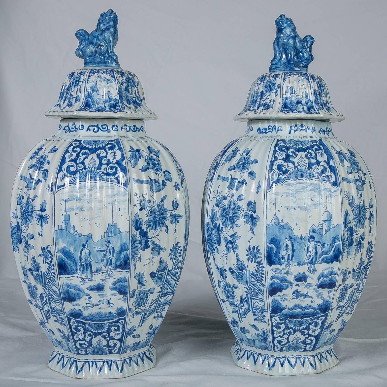 A lovely pair of Dutch delft covered jars with ribbed panels painted in a soft blue with garden scenes and song birds.
Each vase is topped by a foo lion finial (foo lions were traditional protectors of the home).
 