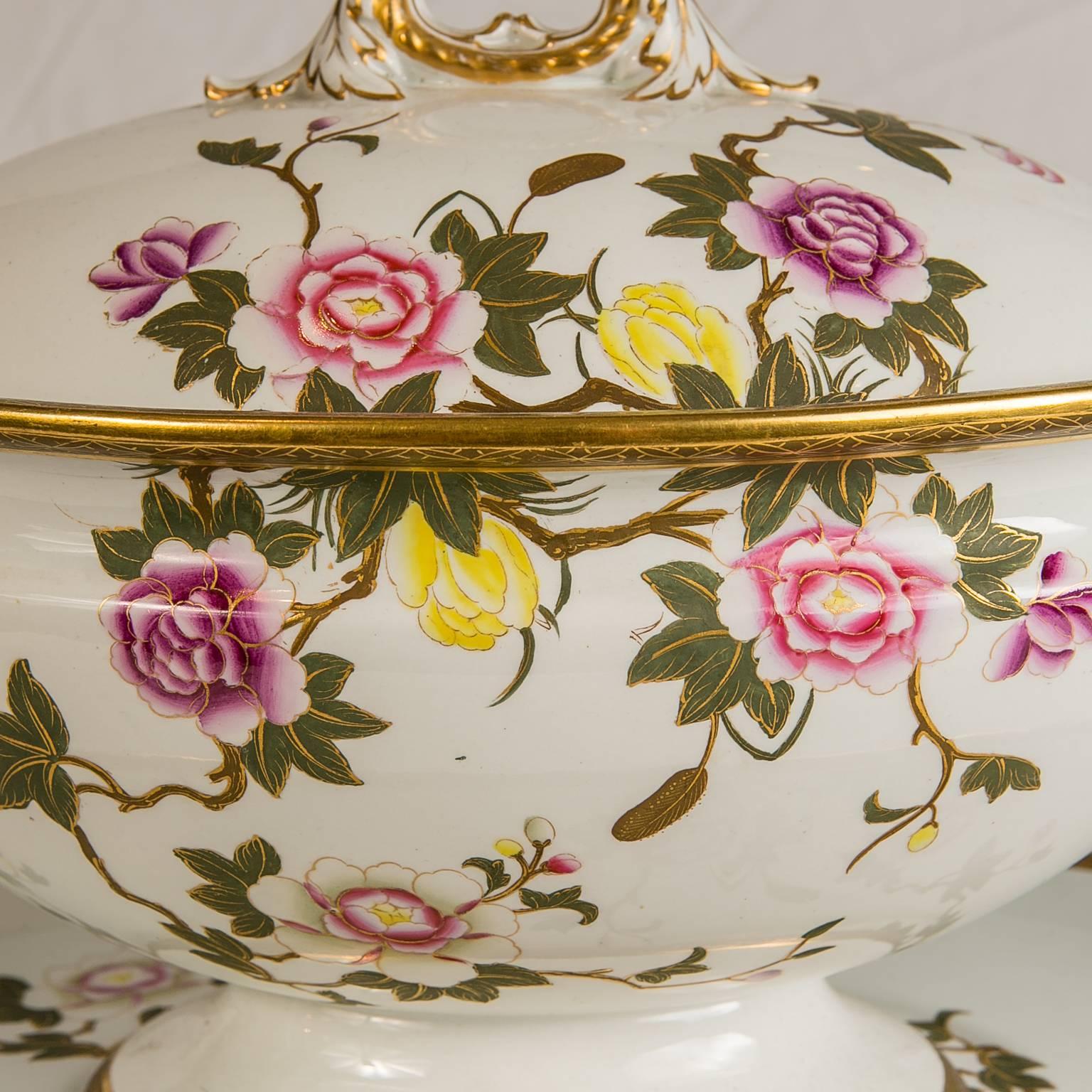 This large Royal Worcester soup tureen and stand is decorated with delicate pink, purple, white, and yellow roses and soft green leaves accented with gold. The finial and handles are made in the shape of branches, adding to the charm of the tureen