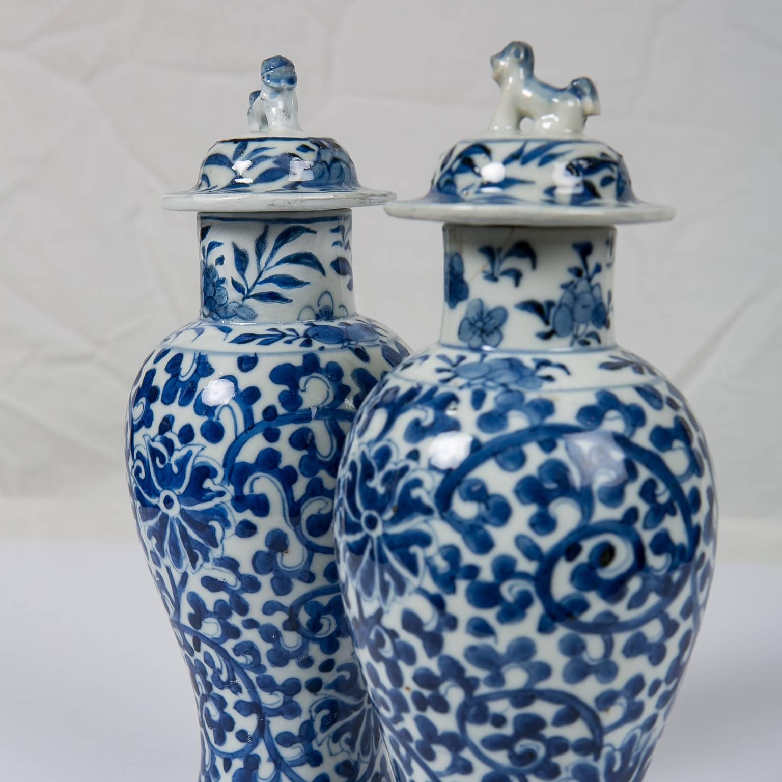 A pair of blue and white Qing dynasty Chinese covered vases painted in deep cobalt blue with a design of Tibetan flowers and scrolling vines. The decoration is harmonious with the shape of the well proportioned vases. The vases are small measuring 9