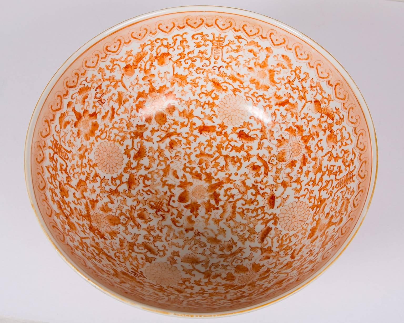 This large Chinese porcelain punch bowl is decorated inside and out with orange peonies , scrolling vines, and traditional Chinese symbols of fertility and beauty. The peonies are symbols of royalty and beauty. The floral scrolls symbolize