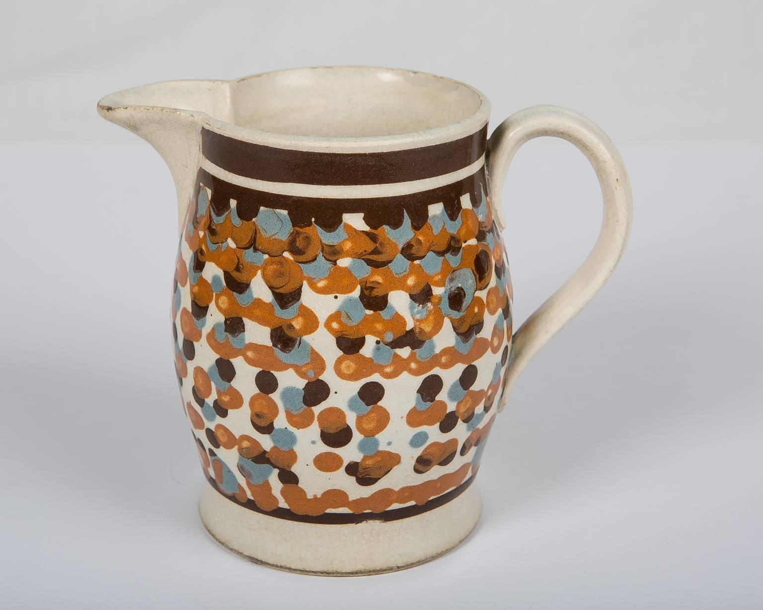 A mochaware pottery jug decorated with multicolored slip, dots. On this jug the slip would have been applied with a three chambered cup. During the process the quills were sometimes separated and dragged on the surface of the jug. The result is an