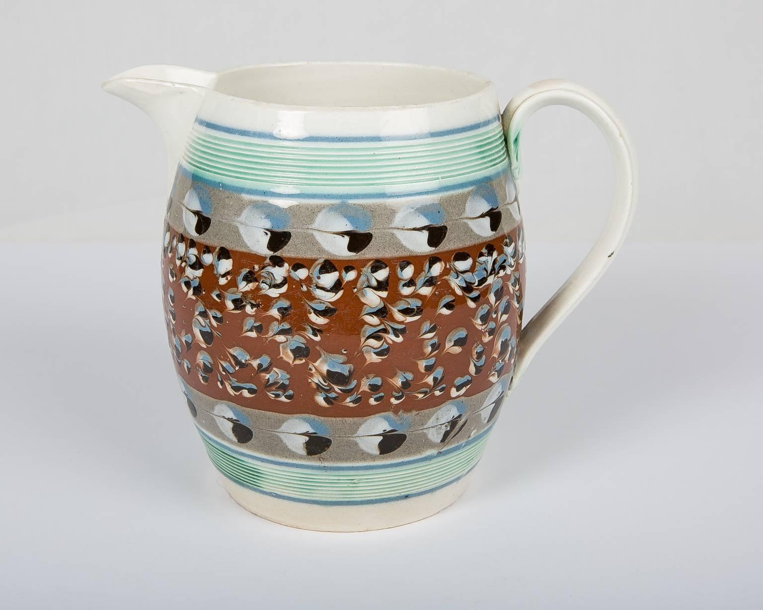 What makes this jug so appealing is the contrast between the large cat's eye decoration set against the pale gray and the smaller cat's eye set against the rust colored ground.
 The cat's eye pattern is based on a round dot usually composed of three