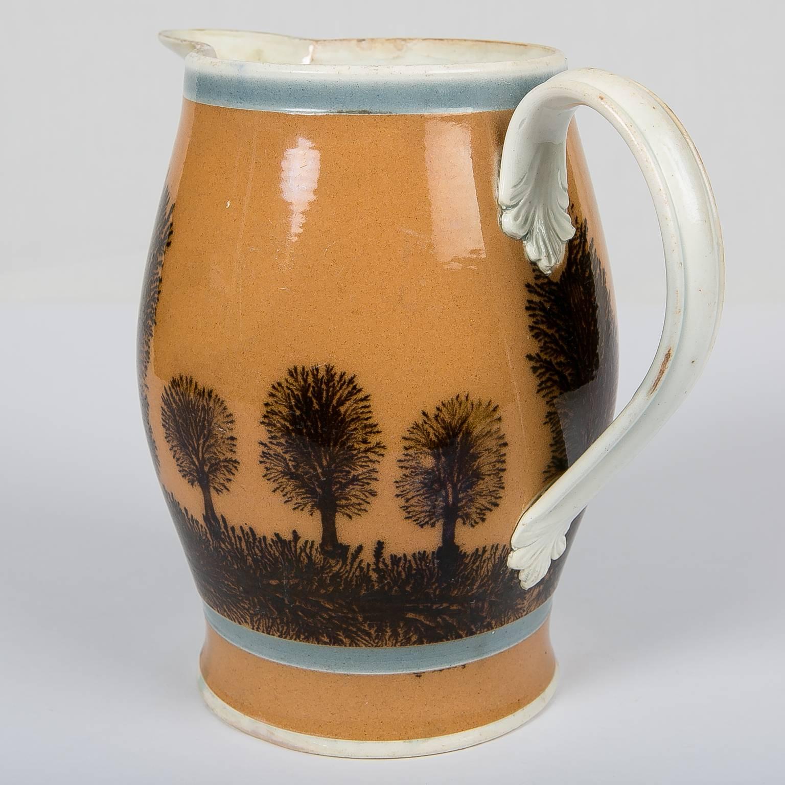 An exceptional Mochaware jug with a wide band of light burnt orange slip molded in an elegant tall shape and decorated with vertical tree-like dendritic designs rising from a horizontal dendritic design of 