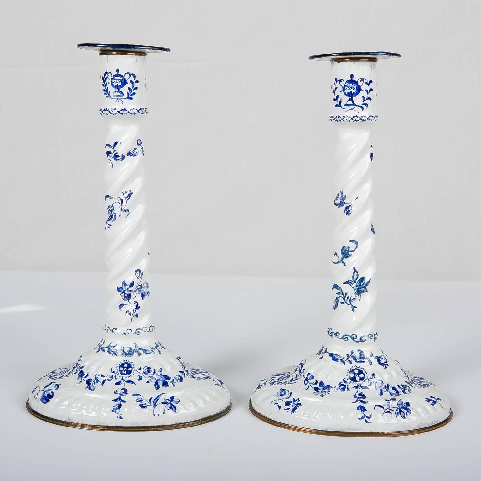 We are pleased to offer this pair of mid-18th century blue and white candlesticks painted with flowers and songbirds. Made by Battersea these enamel candlesticks have typical Battersea rope-twist shafts rising from an oval base and separate small