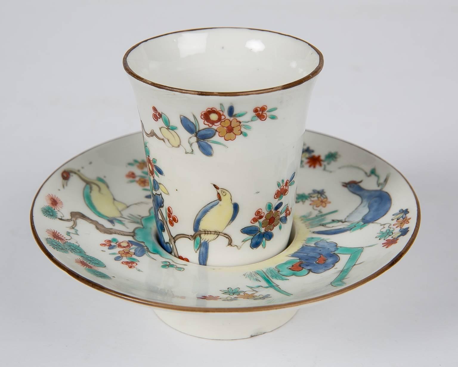 An exceptionally beautiful French cup and saucer in the 18th century Chantilly Kakiemon style showing birds and flowering trees. The style features enamels in a distinctive palette of soft red, yellow, blue and turquoise green painted in an
