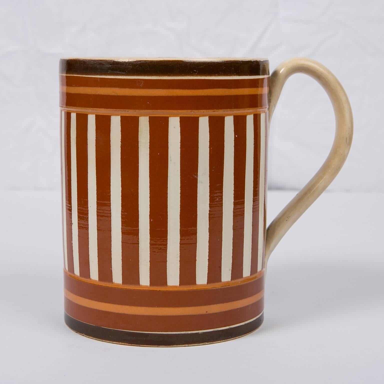 This antique creamware mochaware mug or tankard is slip decorated with both vertical and horizontal stripes in three shades of brown. No two mochaware pieces are the same. Each potter made his own choices in color and design. What makes this mug so