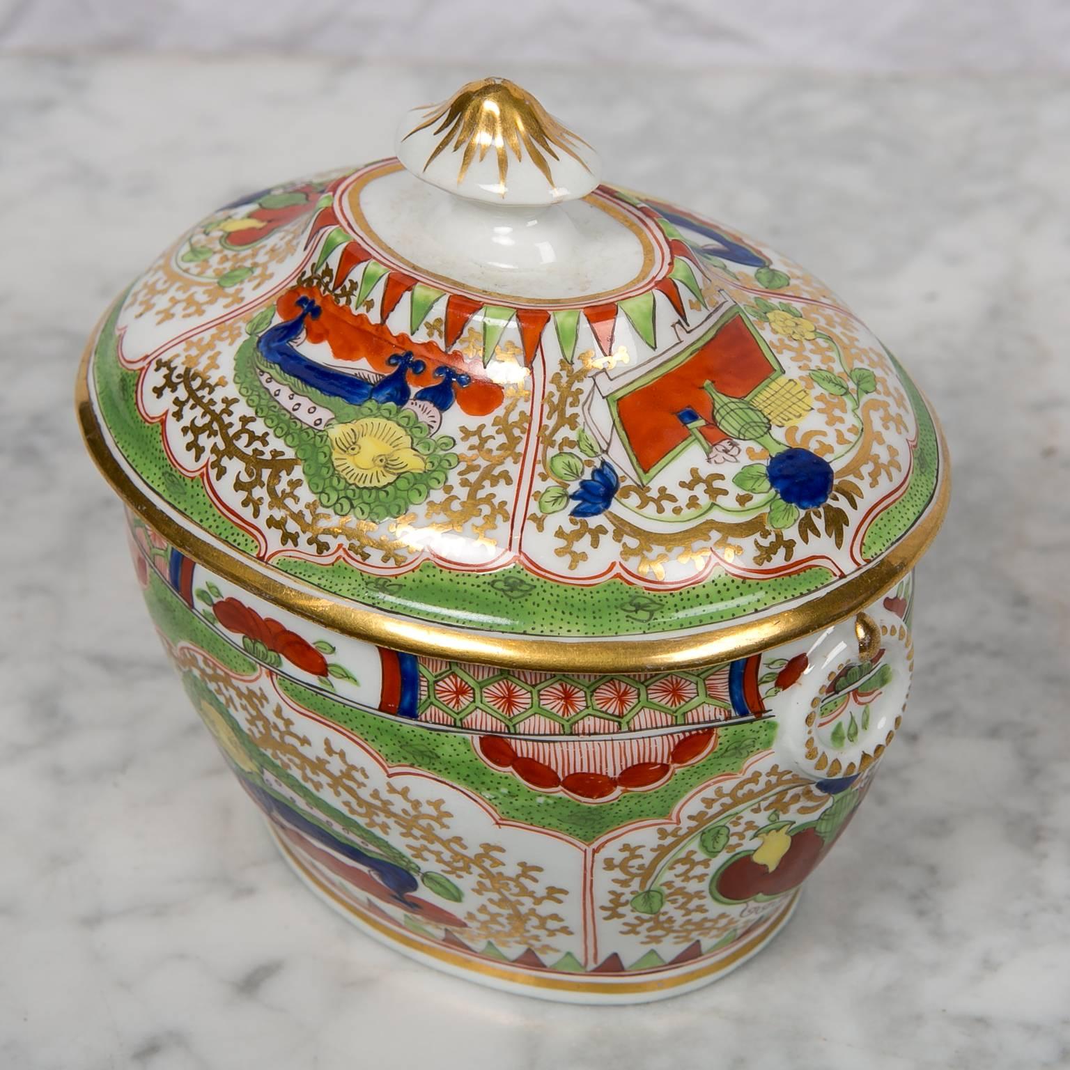 This antique sugar box made by Chamberlains Worcester in the Bengal tiger pattern is painted with lappet-shaped panels on each side showing a mythical beast. At each end of the sugar box is a panel showing objects of good fortune. The border is