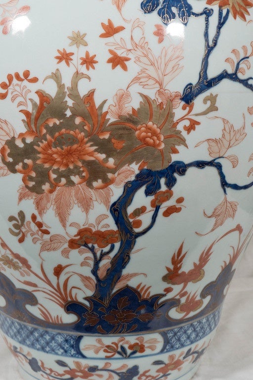A pair of Chinese porcelain vases decorated with an all-over pattern of flowers and flowering fruit trees painted in the Imari colors: Cobalt blue, iron red and gold. It is a striking decoration with lappets and bands of diamonds framing the scene.