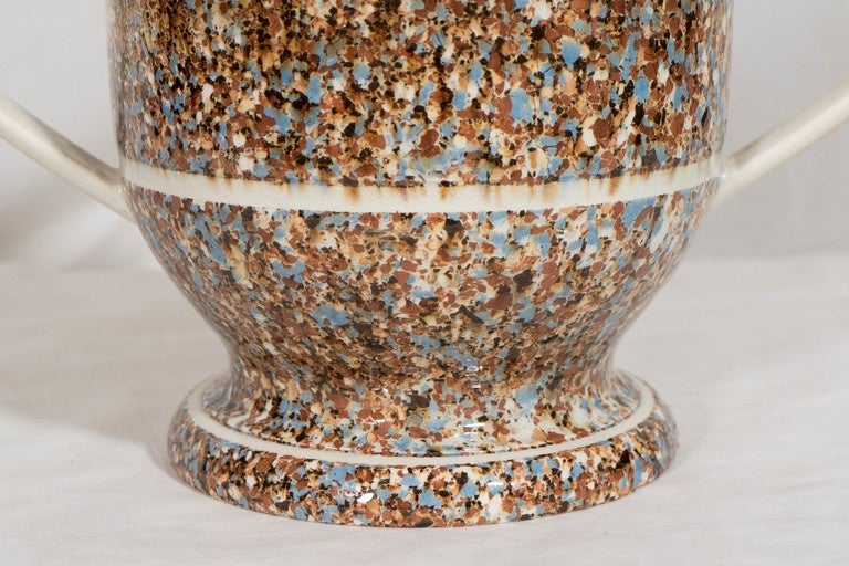A large, two-handled loving cup of inlaid agate ware, the exterior made of brown, blue, and cream glazed earthenware. Surface agateware is a type of Mocha Ware formed by wedging colored clays together, cutting and rolling them like pastry, before