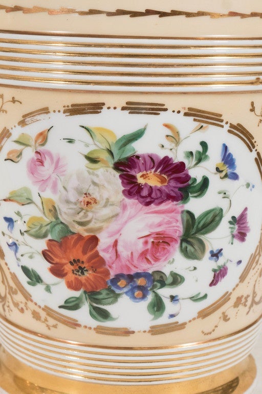 A lovely pair of Louis Philippe Paris Porcelain cache pots (each cache pots comprising a flower pot with drainage hole and a separate fitted stand). Hand painted with a cartouche of flowers in bright colors on a richly gilded peach ground. They have