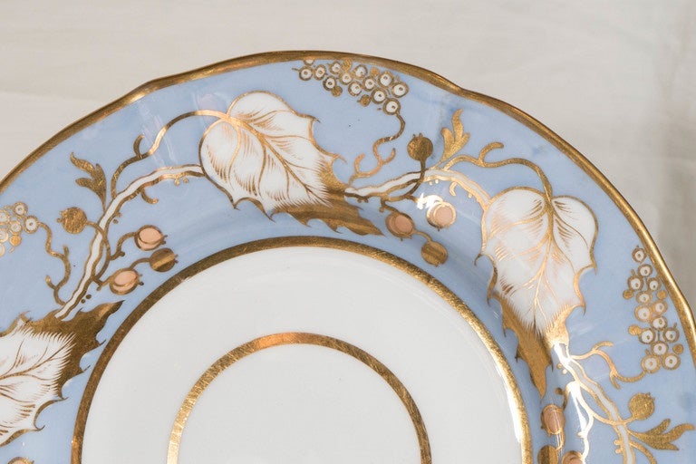 A ridgway dessert service with a light blue ground decorated with white and gilt holly leaves and pale orange berries.
The service includes 19 pieces:
A dozen round dishes, 
three cake plates (only 1 shown),
three shell shaped serving