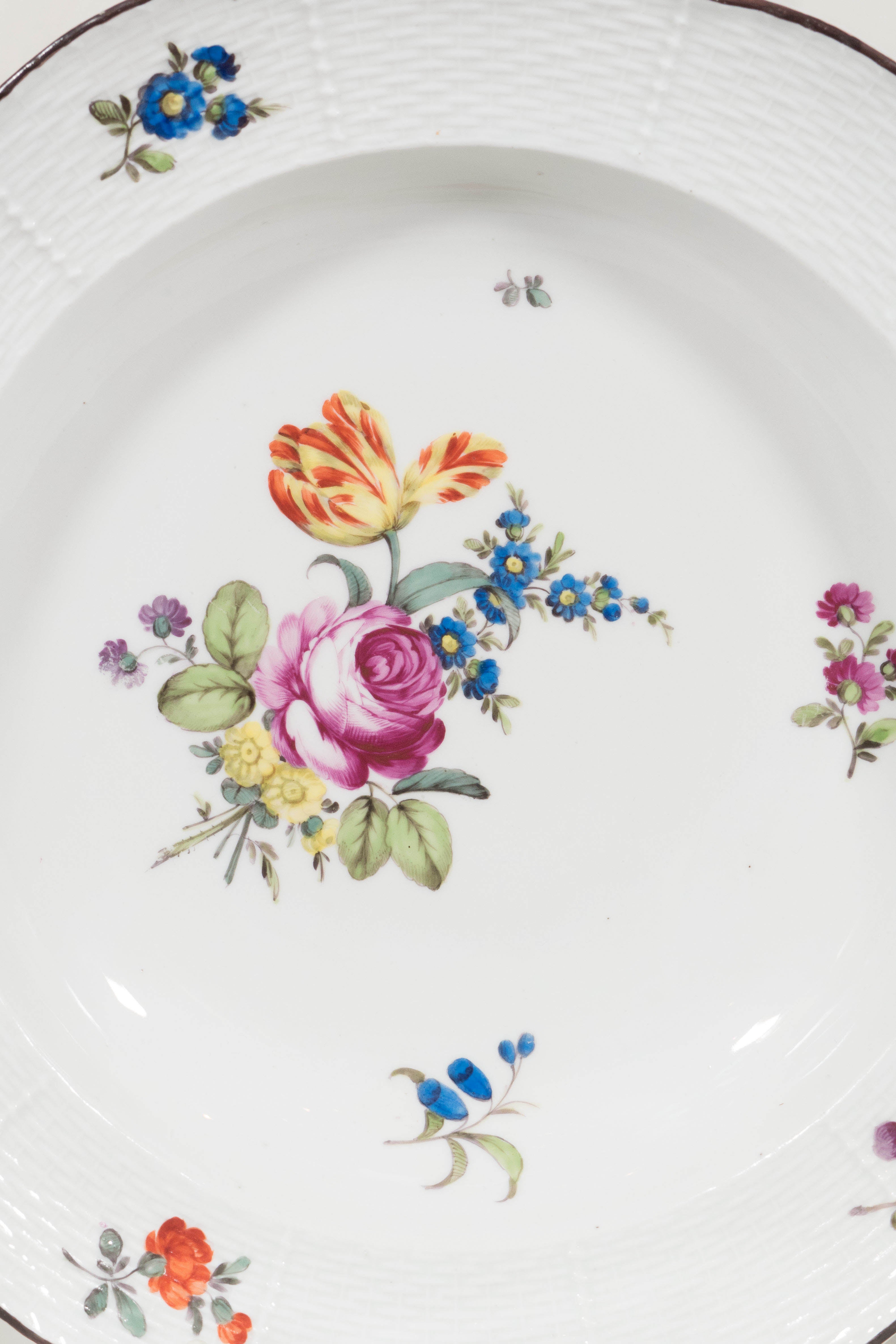 A set of a dozen mid-18th century Vienna hard-paste porcelain plates beautifully hand-painted in enamels with one large bouquet and detached sprays of roses and other flowers. The ozier border with a band of fine basketwork and a brown-line lobed