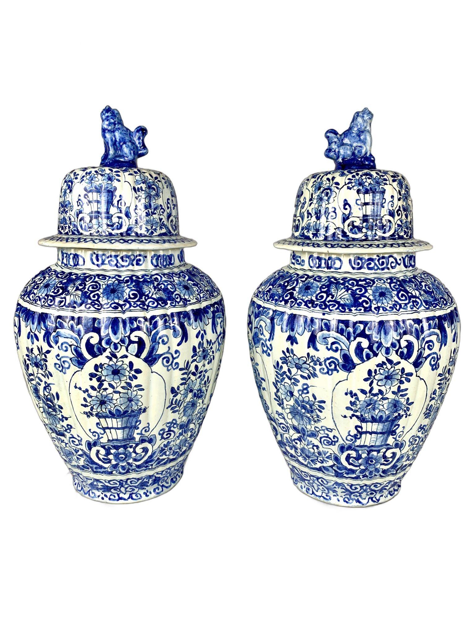 This exquisite pair of large blue and white Delft jars was hand-painted in the Netherlands during the late 19th century, around 1880.
The design features shaped panels, each depicting a scene of a vase filled with flowers and foliage, surrounded by