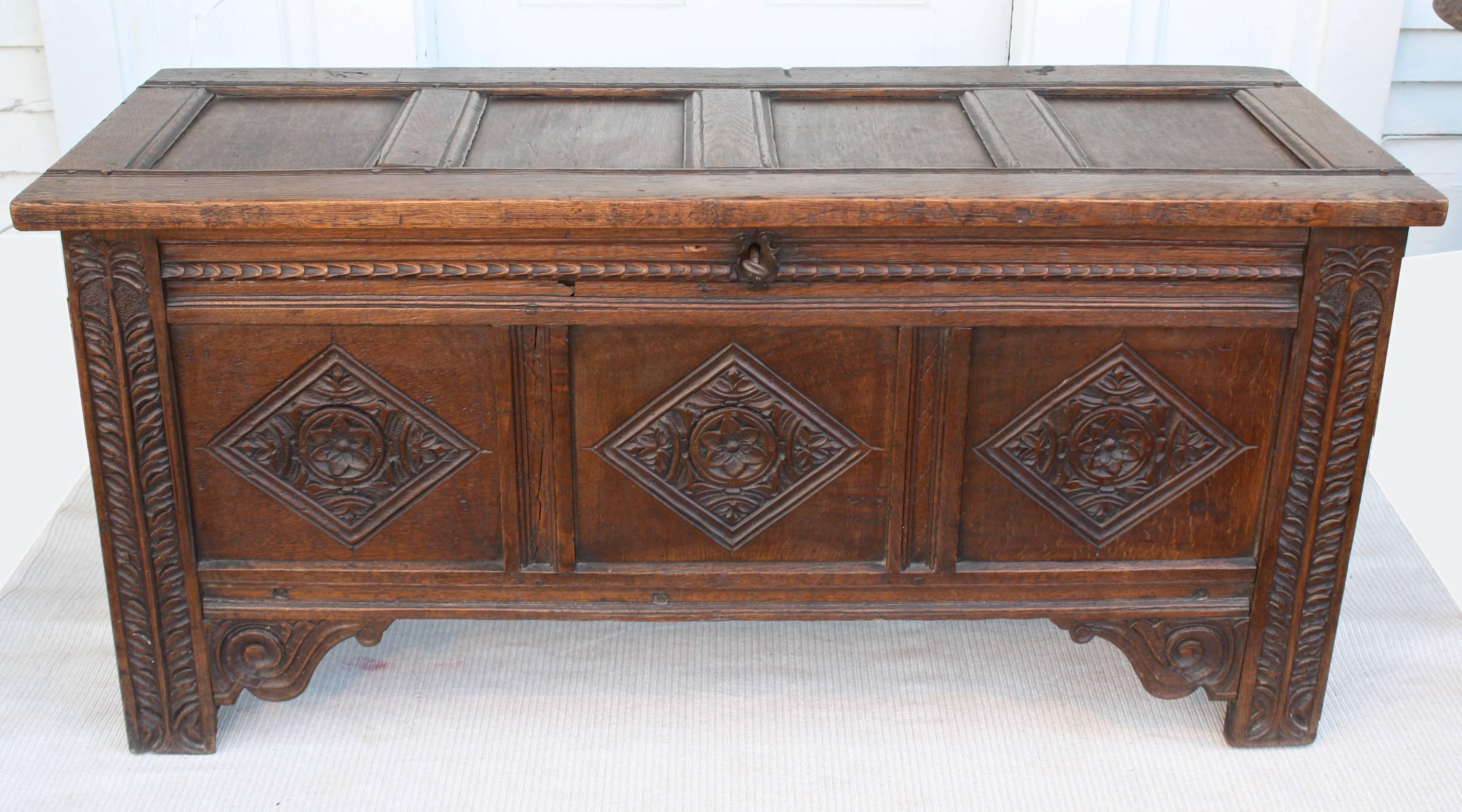 A hand-carved oak Charles II Restoration Period coffer or blanket chest, with a working keyed lock. Its sides and top are paneled. Its front has three large foliate carved diamond panels and distinctive vine carved corner column facings.