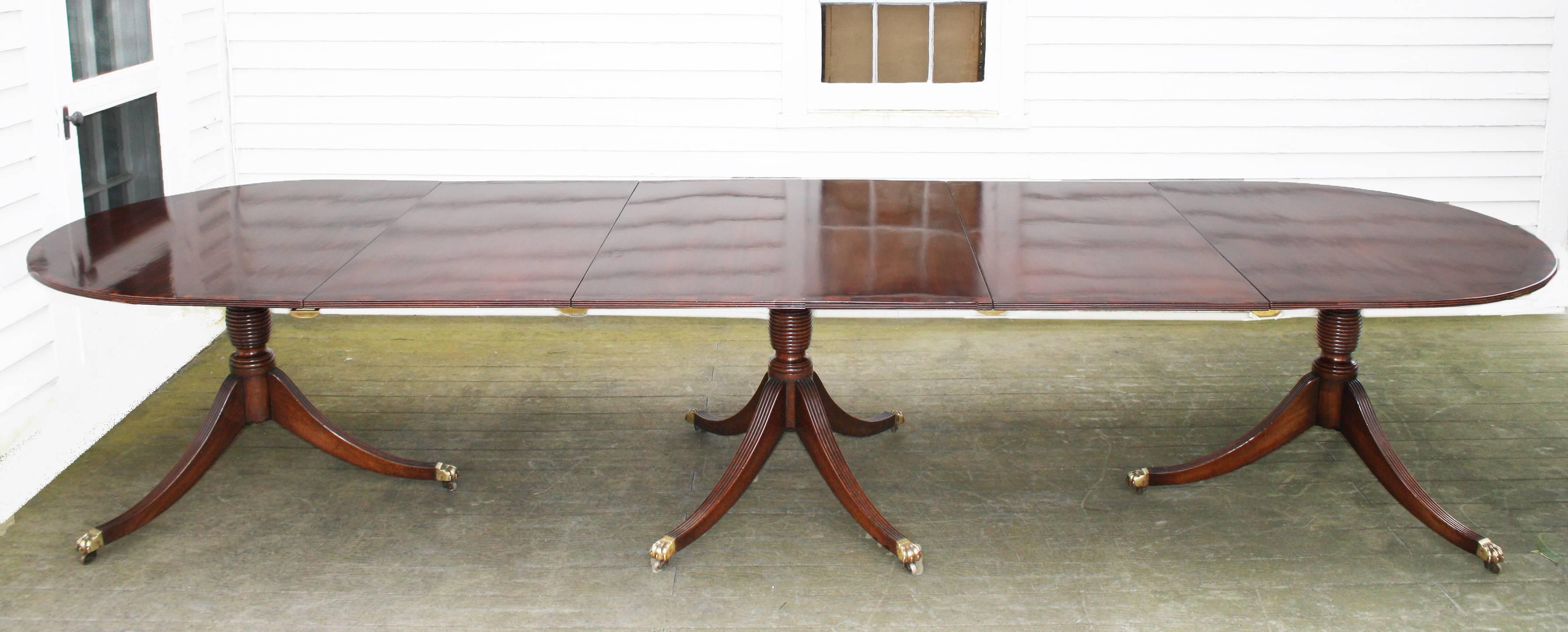 A solid mahogany hand-planed, carved and turned triple pedestal banquet table, with two 23.75