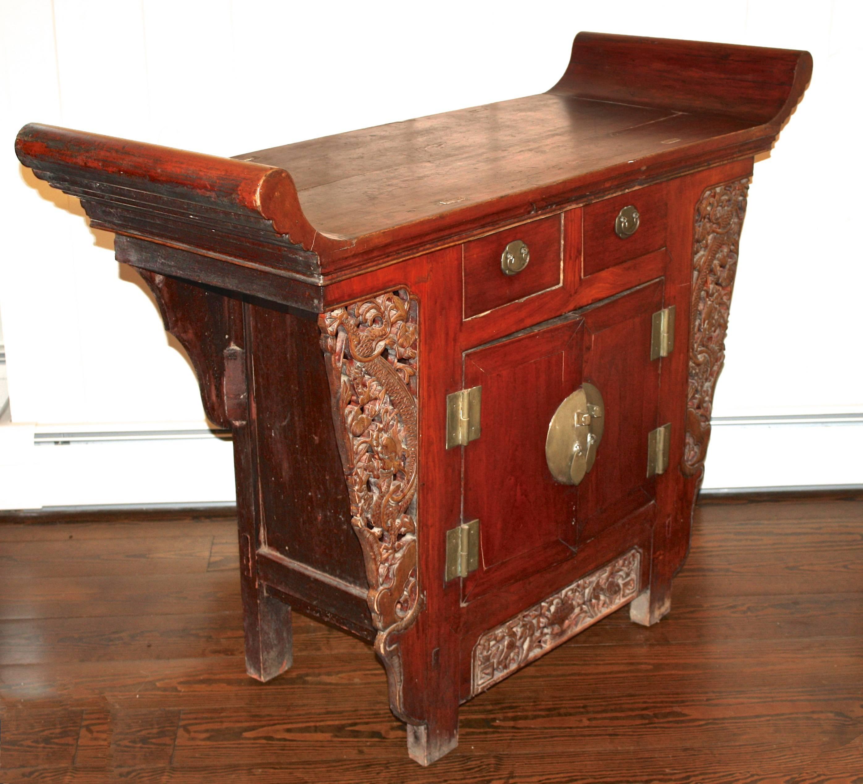 An ornate South China altar cabinet of the Tongzhi period. Pierce-carved jabots and a frieze panel decorate the trestle structure; usually open, yet in this case enclosed by side and back panels, and fronted by two drawers over two doors. The