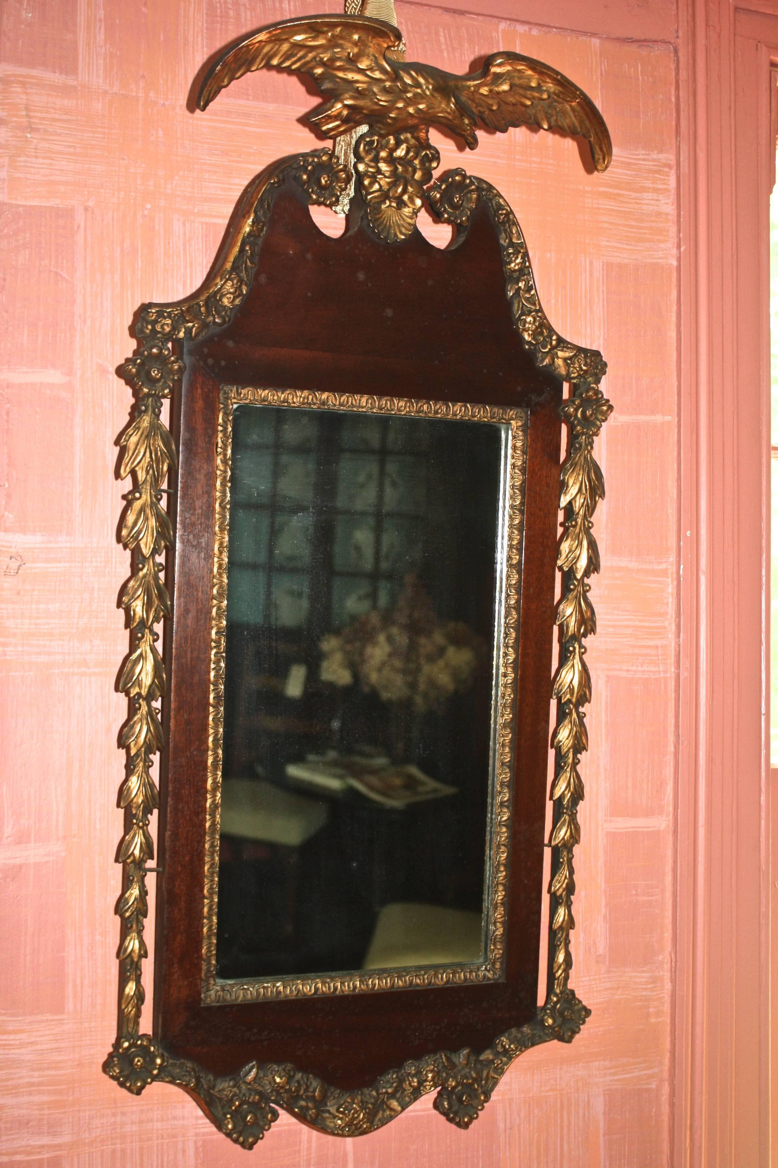 A mahogany framed and carved gilt wood adorned mirror with an eagle surmount.  The gilded eagle and especially the foliate elements, are fine, complex, and well executed.  The plate (mirror) appears to be original.  Made in the manner of American