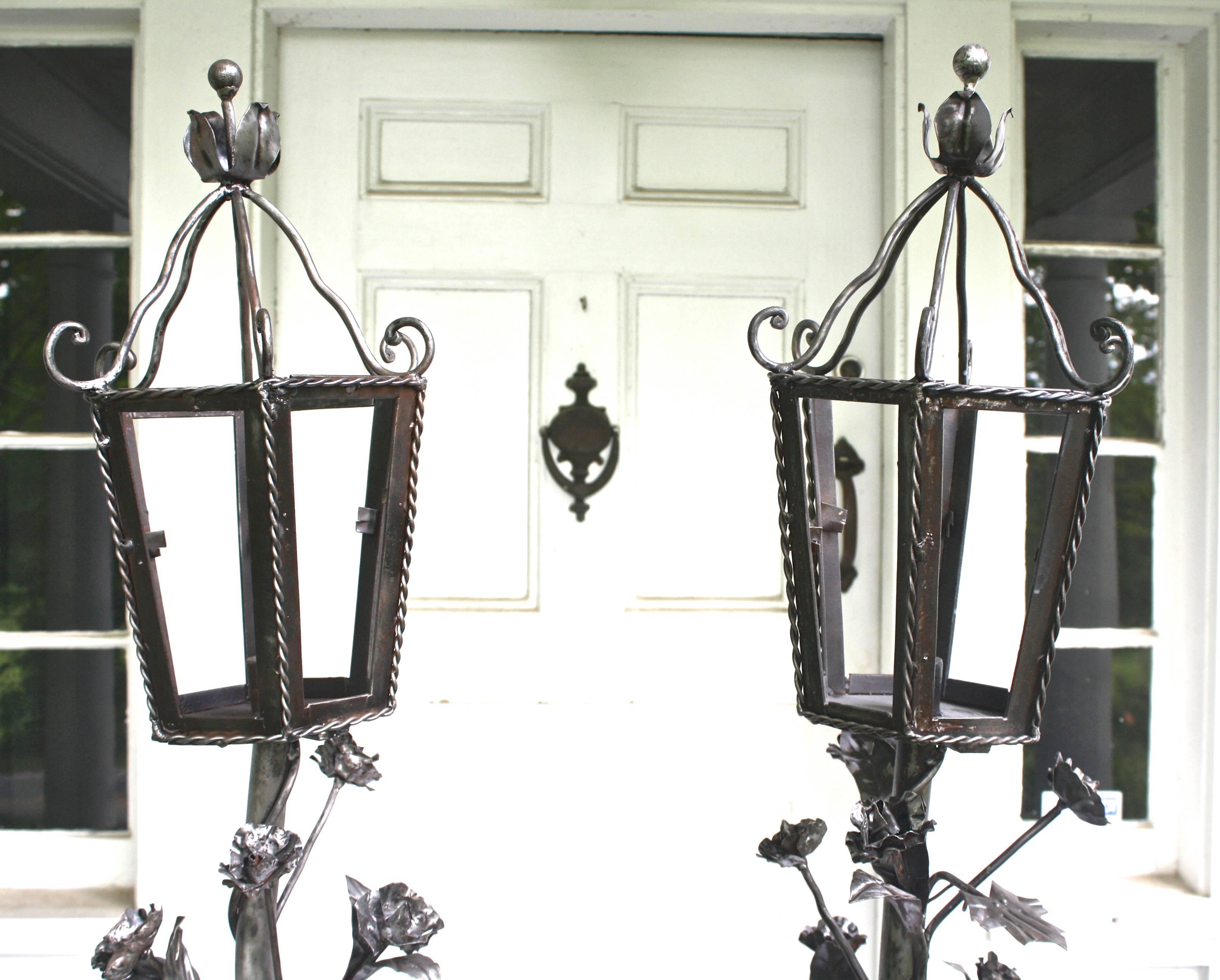 A matching pair of wrought iron, twisted floral-vine covered, hexagonal lantern torchieres.  Originally made to serve as lighting for a botanical conservatory, piazza, or covered porch; this rare and eccentric pair may be placed anywhere indoors