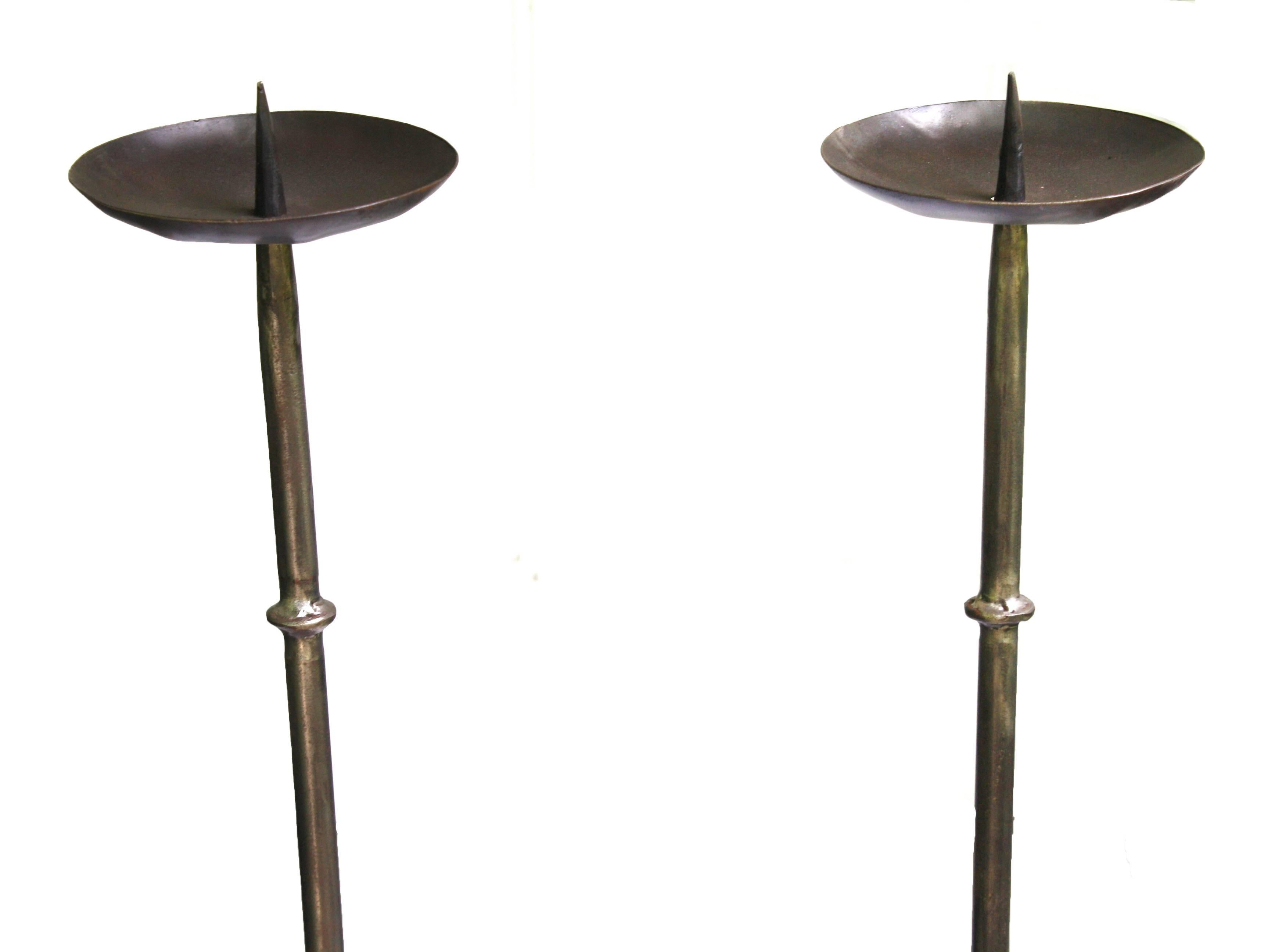 In the manner of mid-18th century Georgian iron-cast tripod prickets; each with four ring turnings, generous bobeches for wax drippings and standing well over four feet tall with candles. Just cleaned and fully restored by a master metalsmith; they