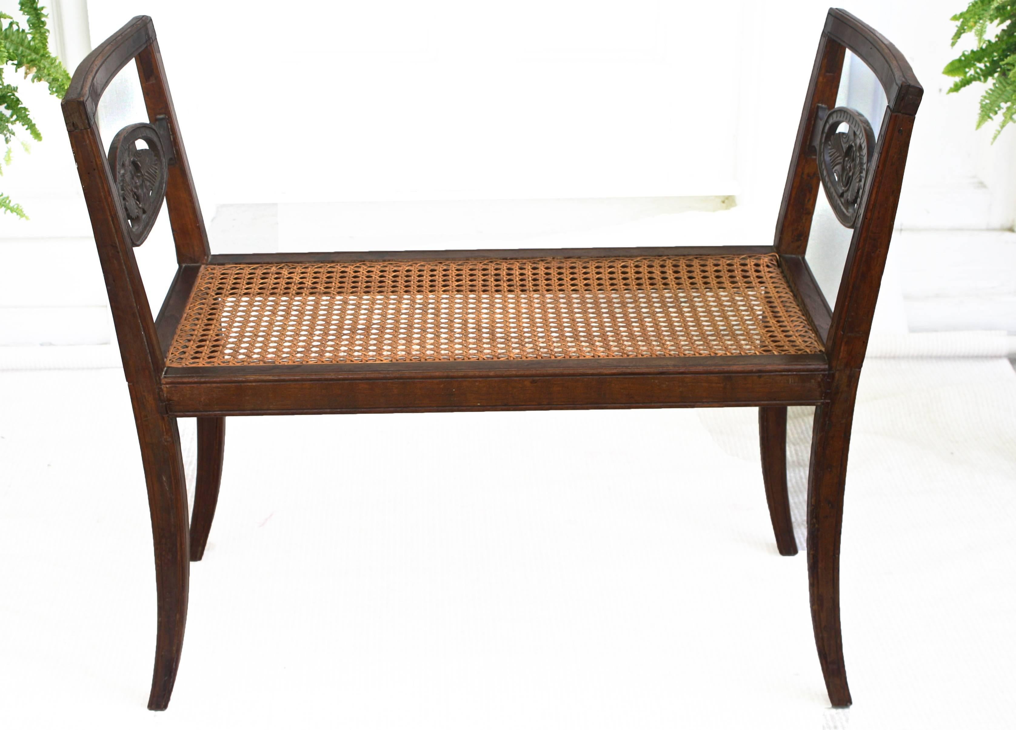 A mahogany framed and cane-seated window bench with splayed legs; the side
arm supports flare slightly and are centred with foliate-carved oval medallions.
Likely Florentine origin.