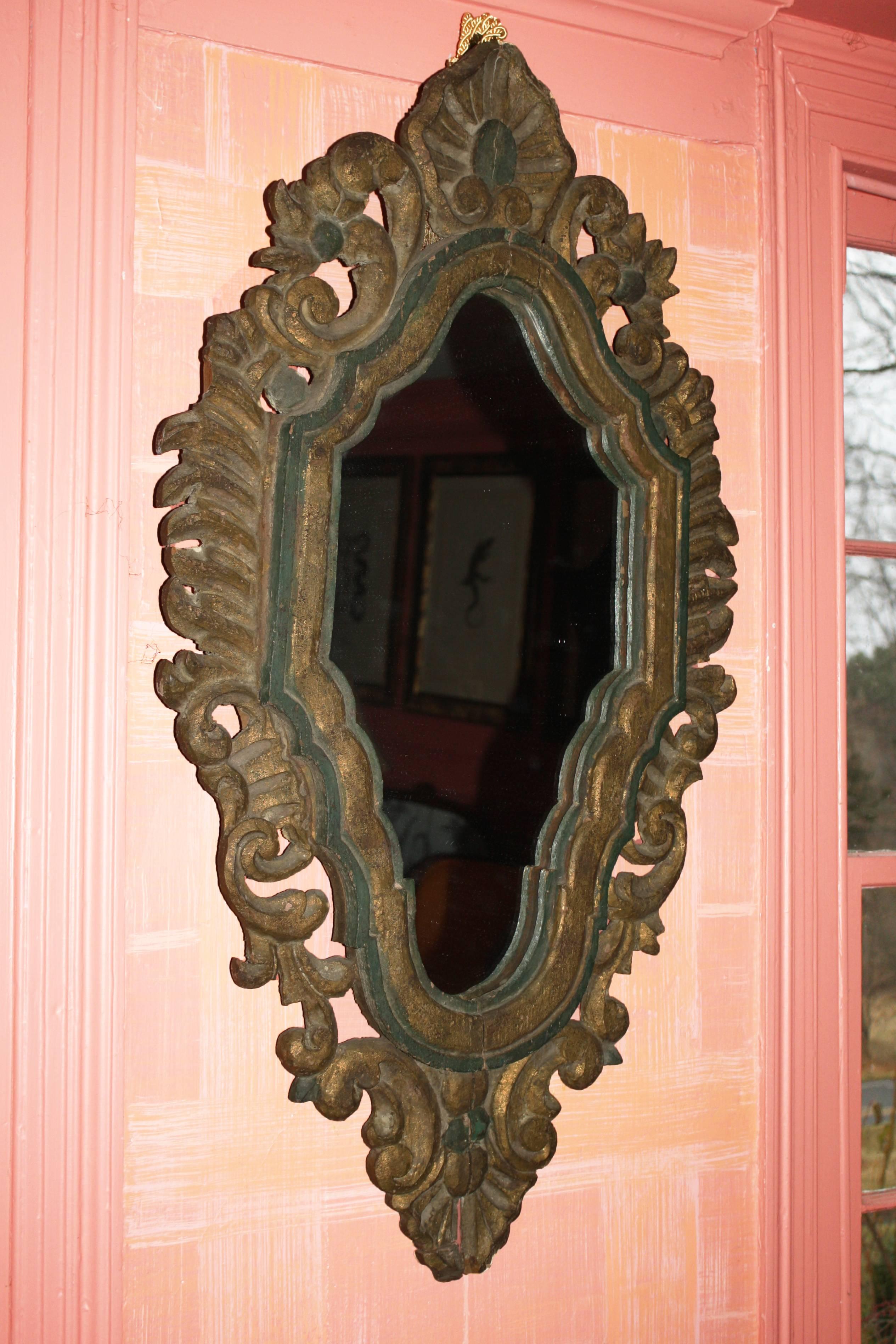 An ornately pierce-carved foliate framed elongated hexagonal mirror. The emerald green paint and water gilding appear to be original, with minimal 'in-painting' conservation. Ex: the Continental furniture collection of a National Historic Register