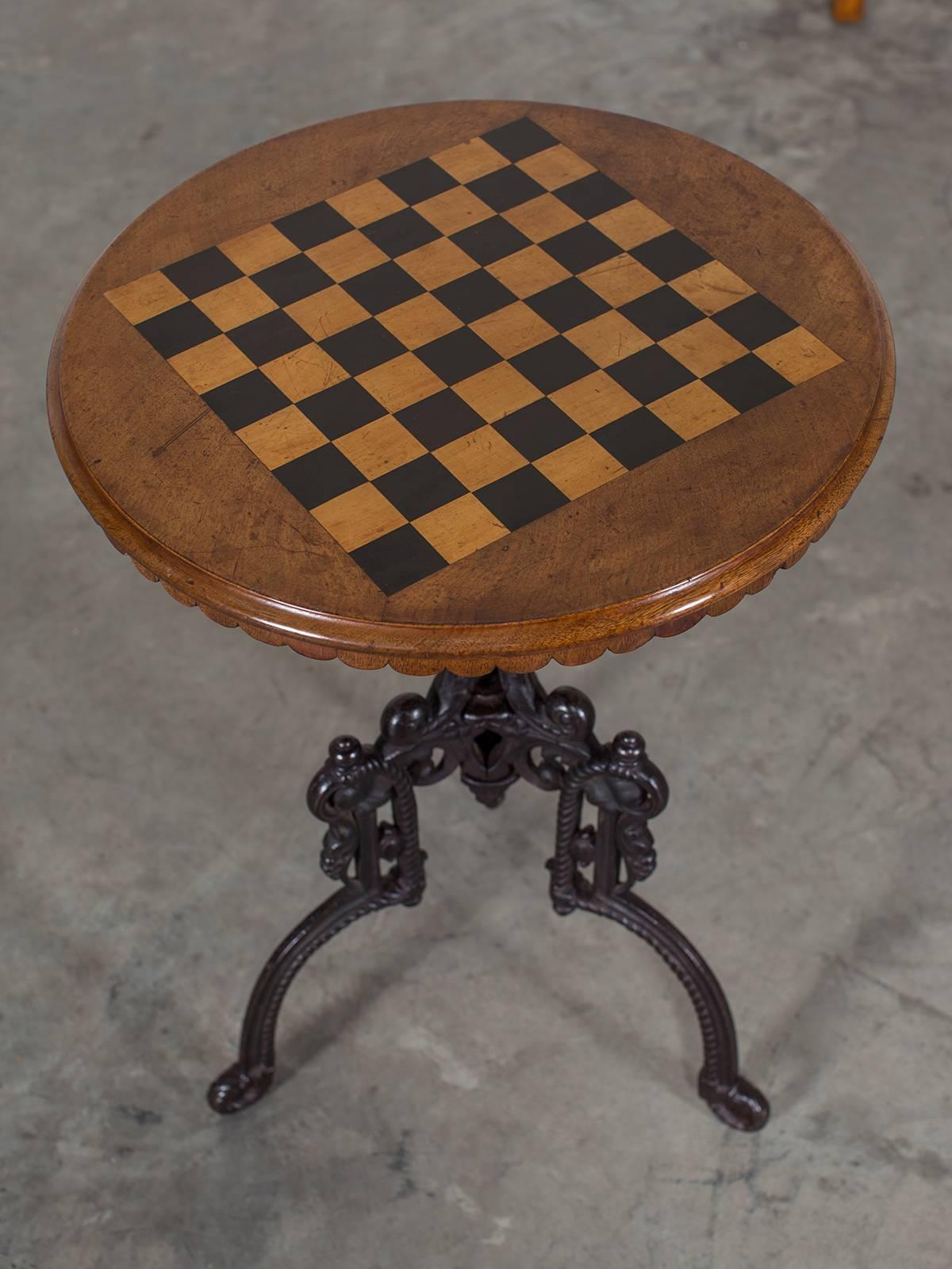 This handsome Belle Époque period, circa 1880 chess table stands upon a superb quality cast iron base that provides both visual beauty as well as excellent stability. The circular tabletop frames a regulation size chess board with the squares made