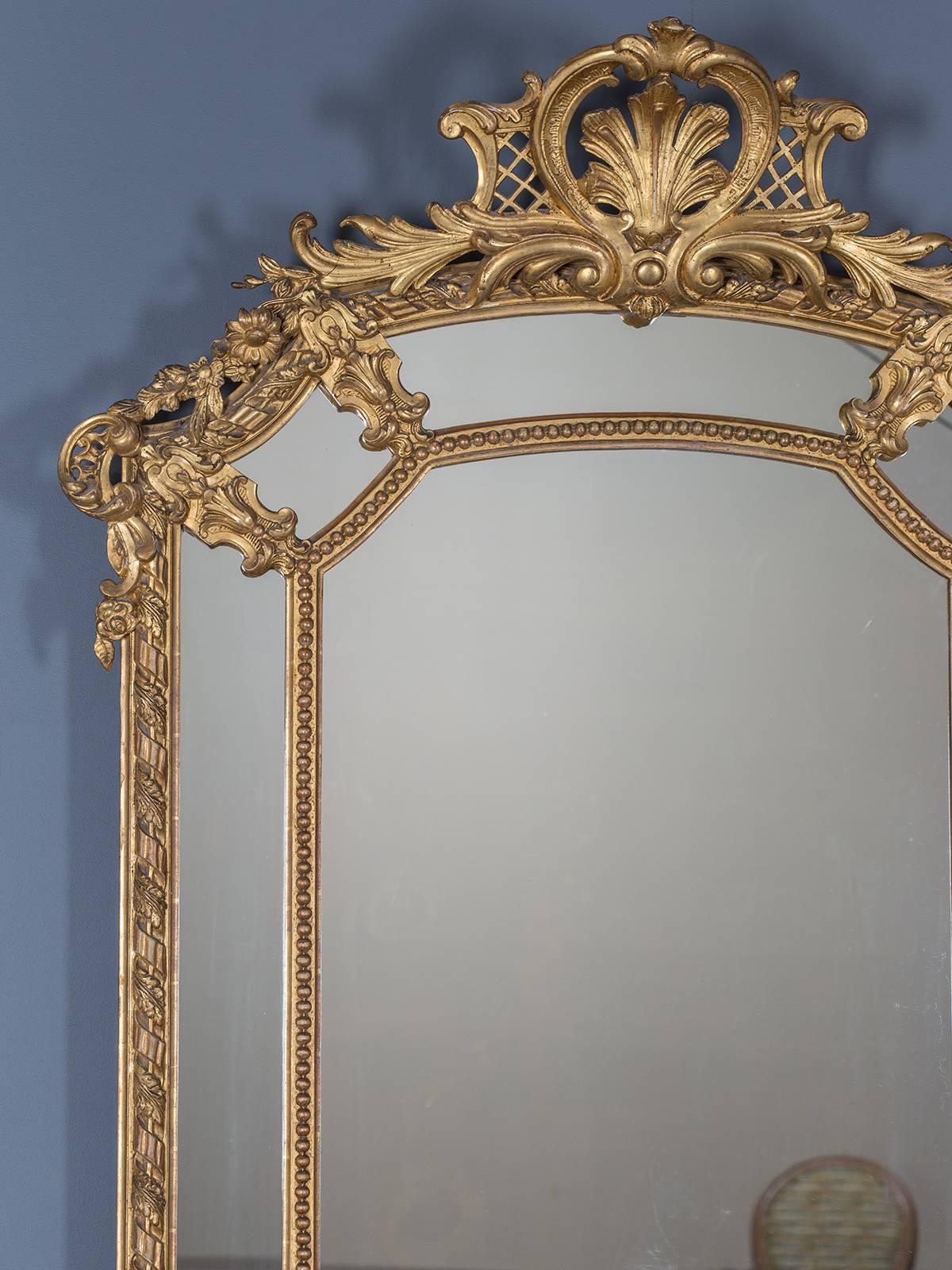 The bold architectural style of this French antique mirror circa 1885 is Régence in style taken from the era when Louis XV was too young to assume the throne of France. The transition in taste from the stately presence of Louis XIV to the lovely