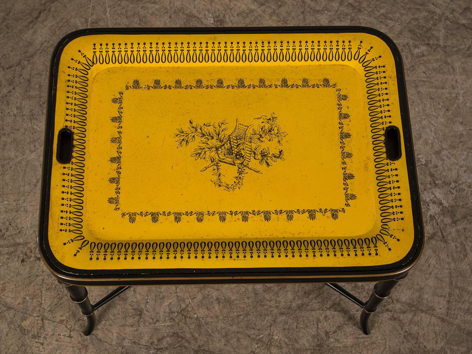 A handsome French painted tôle (metal) tray table from France circa 1880 done in the style of porcelain from Creil in the traditional yellow and black now mounted on a custom painted stand having four carved faux bamboo legs joined by a stretcher.