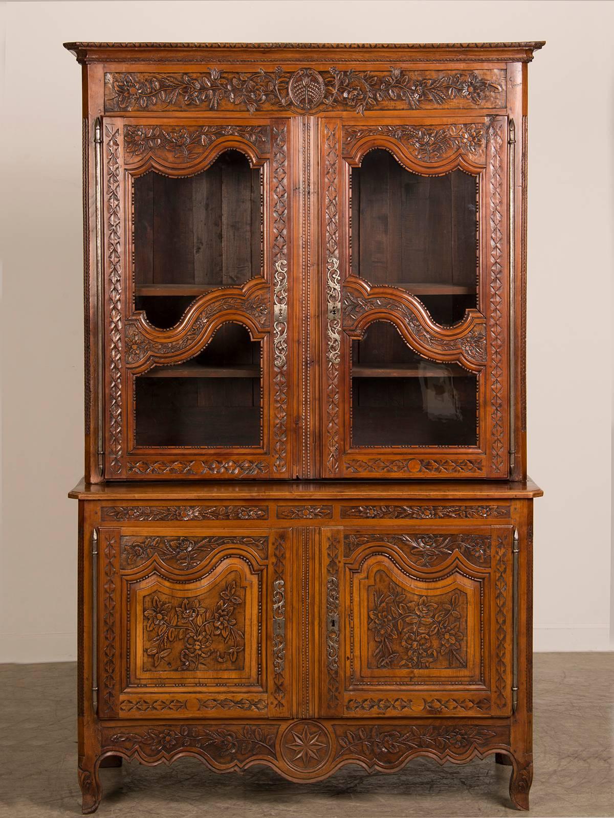 A striking antique French Louis XV period carved cheerywood buffet à deux corps, circa 1760 now having a lighted interior for display. The extraordinary carving across the front facade of this antique French buffet showcases the best of French